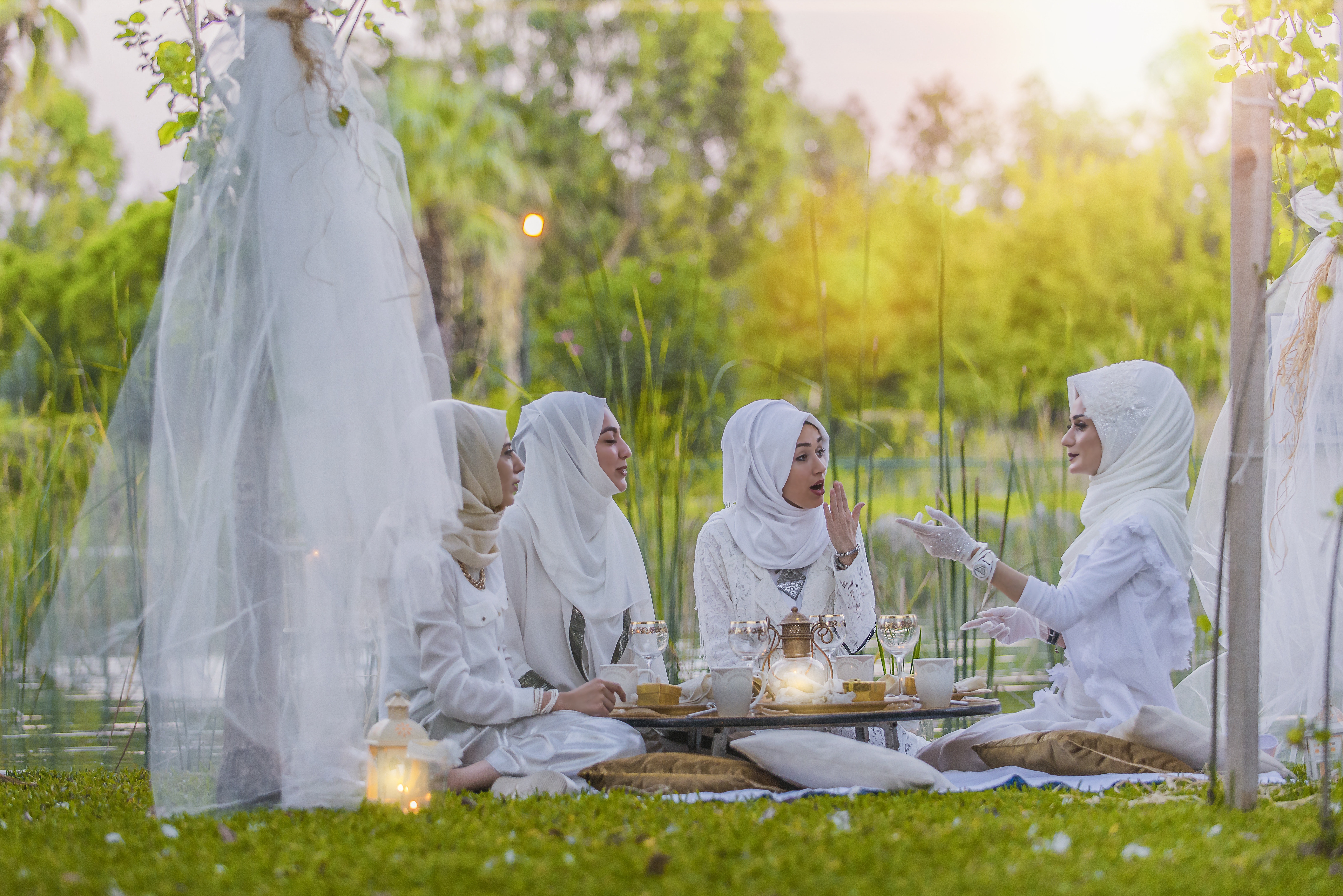 4 women in white abaya wedding gown having picnic near trees photo