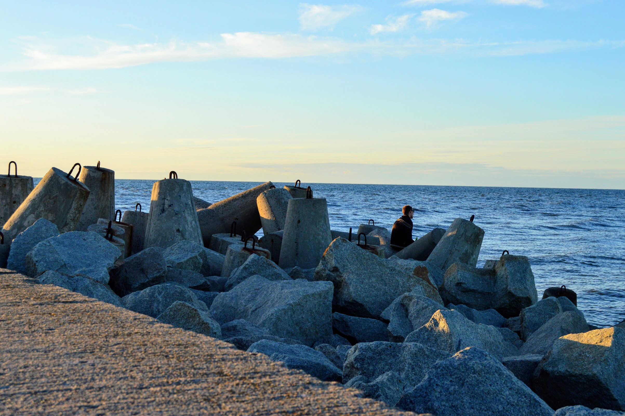 A man sits among tetrapod breakwater on the baltic sea photo