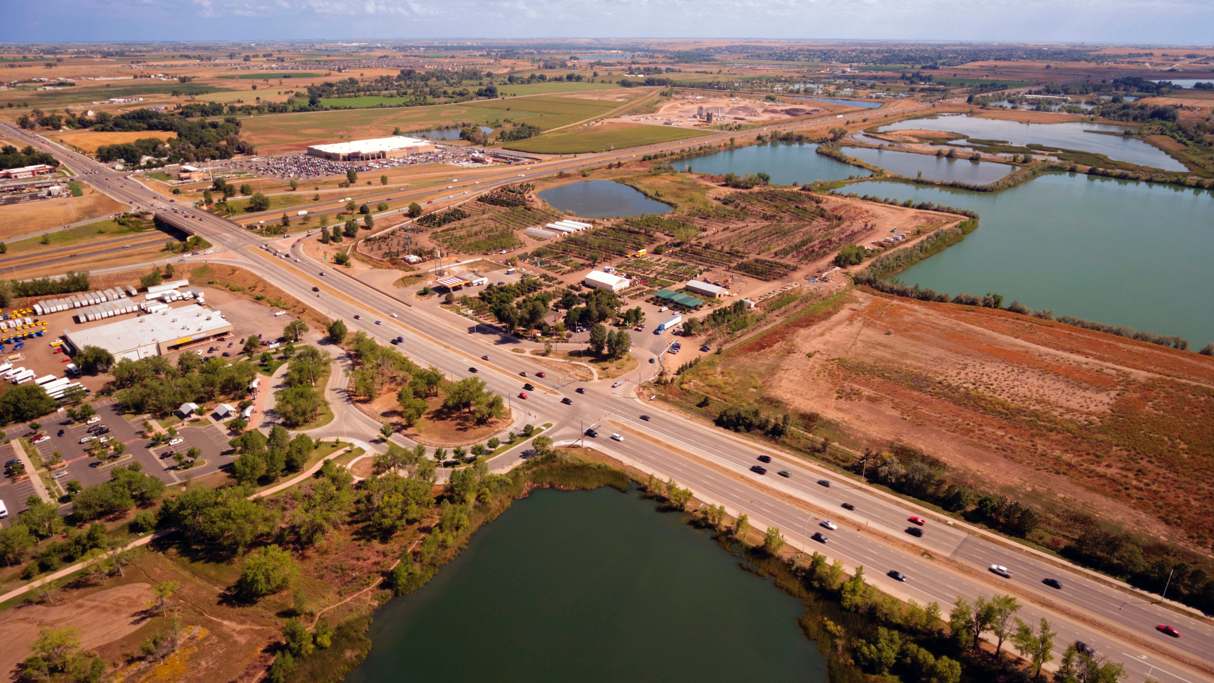 Aerial photography of an open road with cars near city and lake during daytime