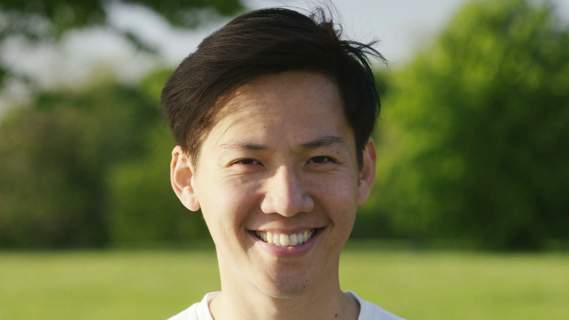 Portrait of smiling asian man looking to camera, in slow motion ...