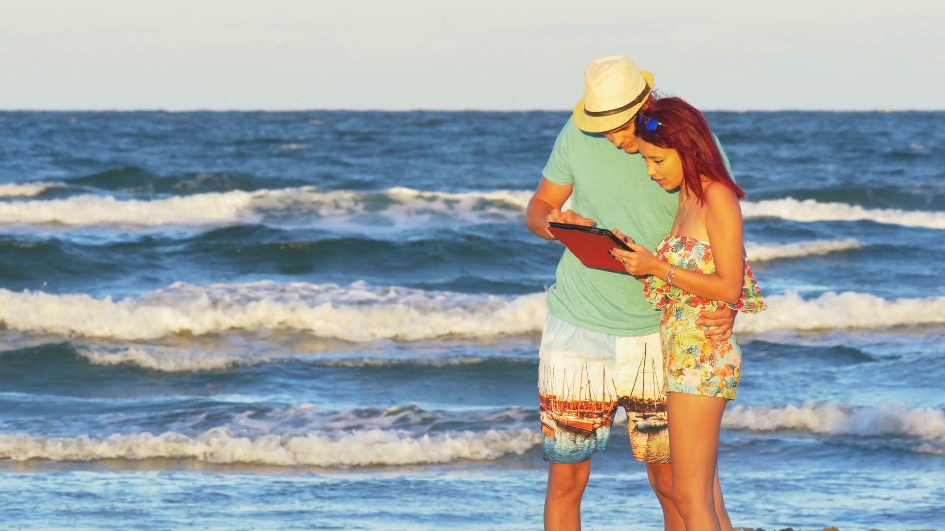 Romantic couple kissing at the seaside and holding a tablet pc Stock ...