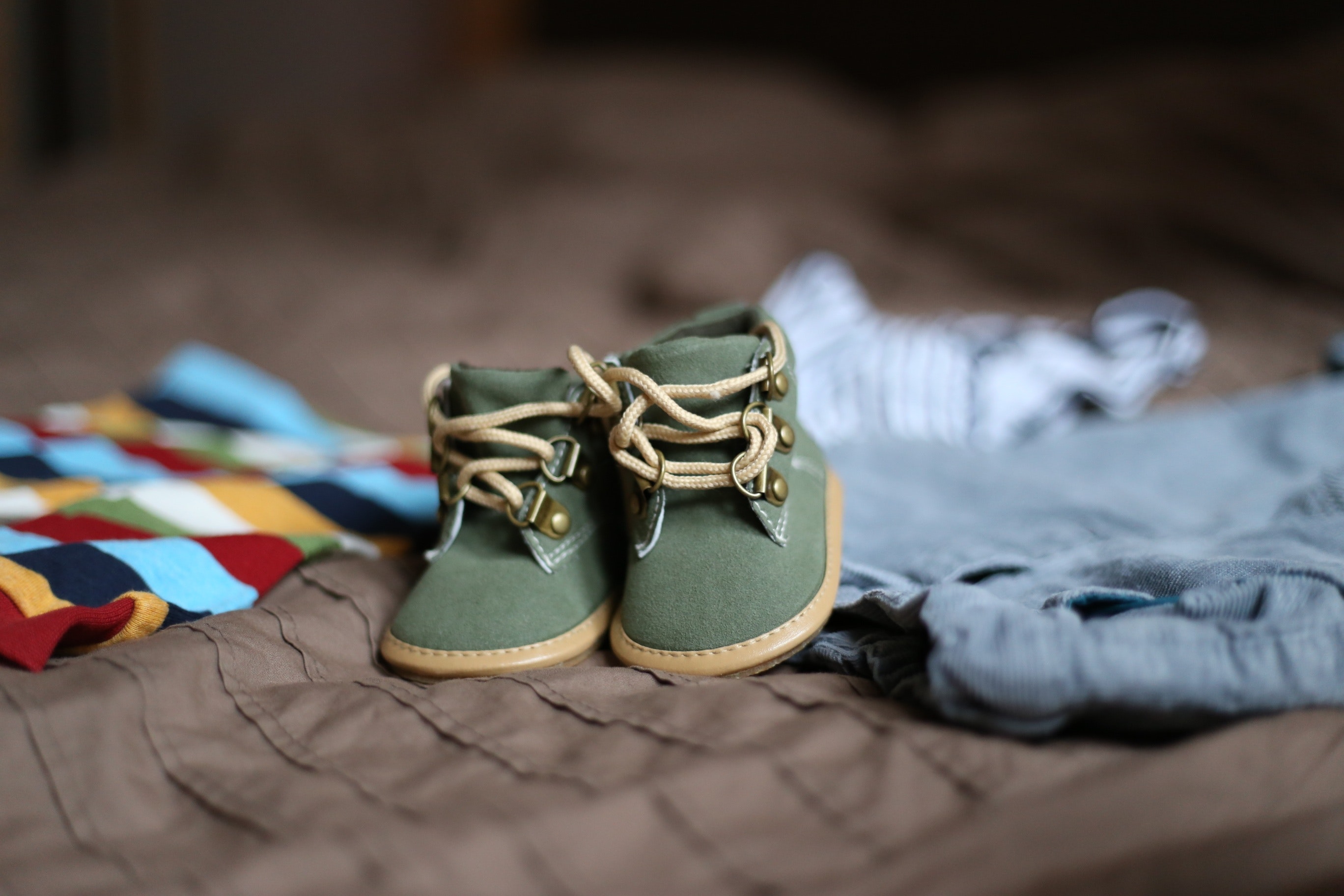 Baby's green and beige sneakers on brown textile photo