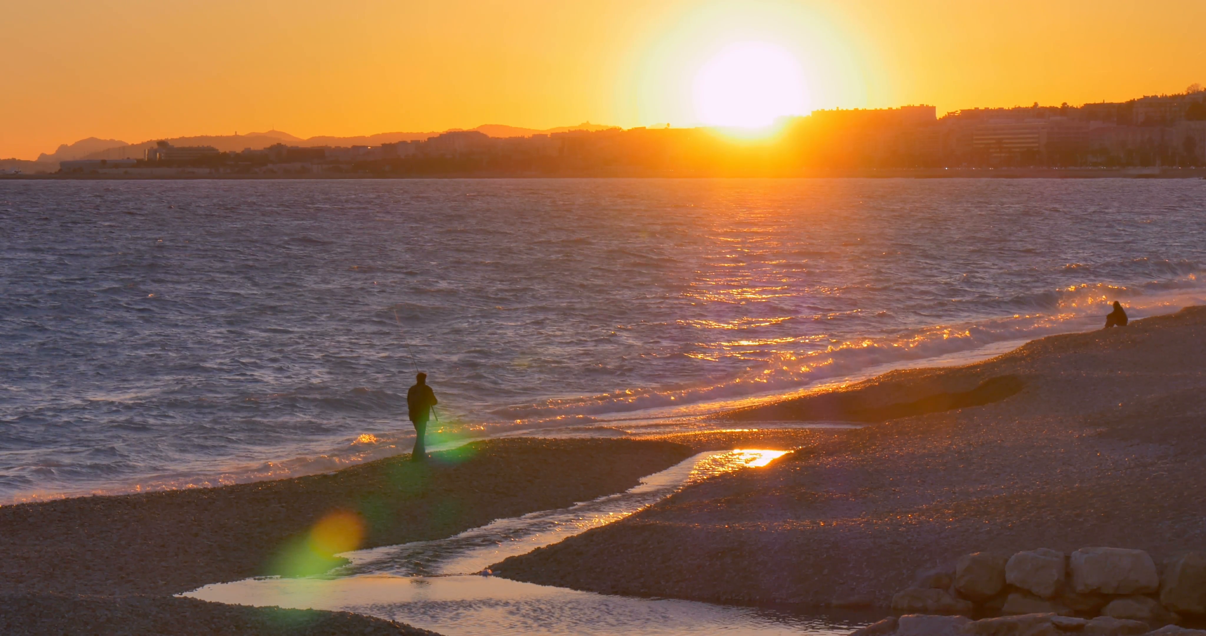 Fisherman walking on the beach in Nice during sunset, south France ...