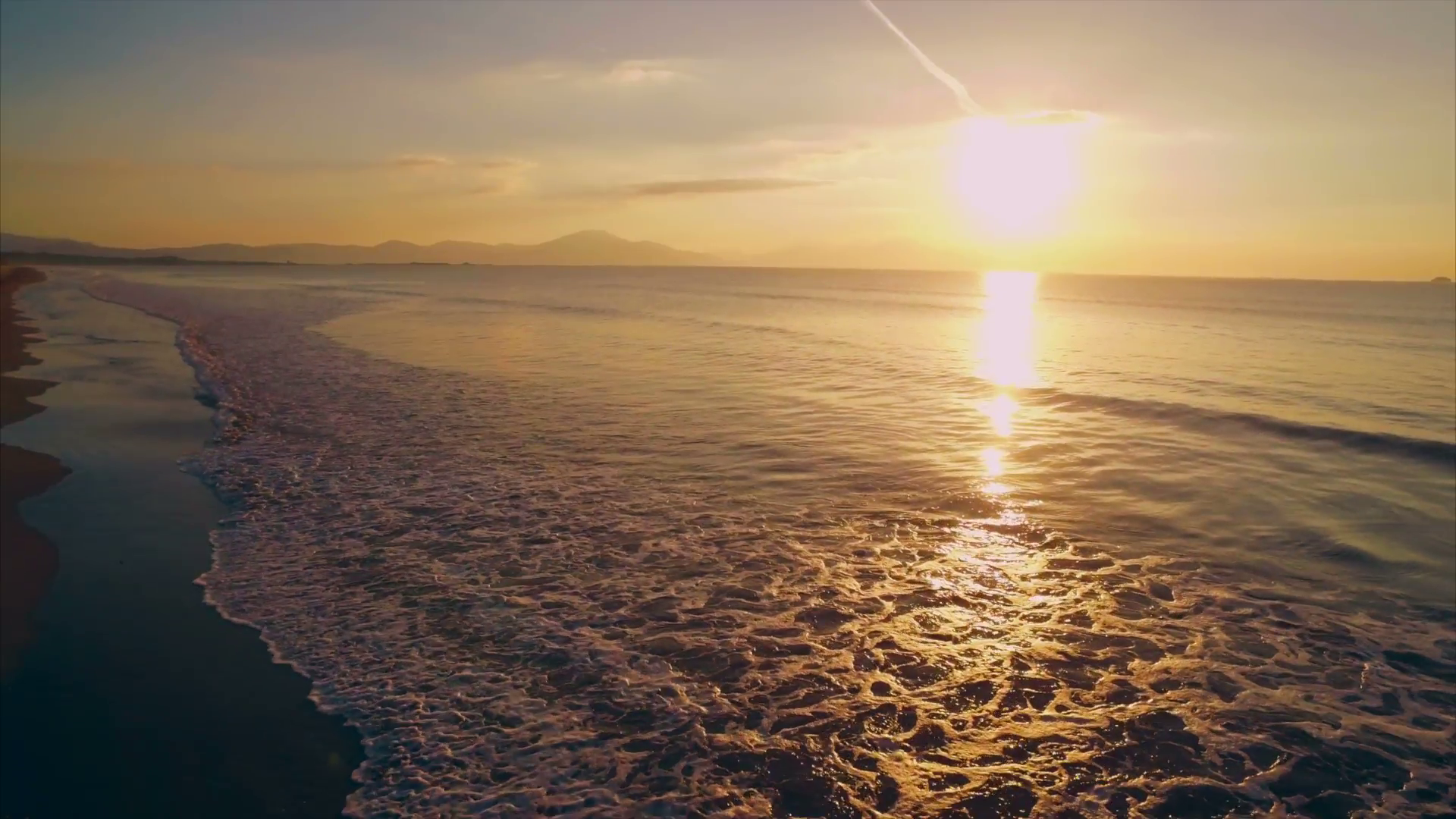 Scenic drone footage of waves reaching beach during sunset. Slow ...