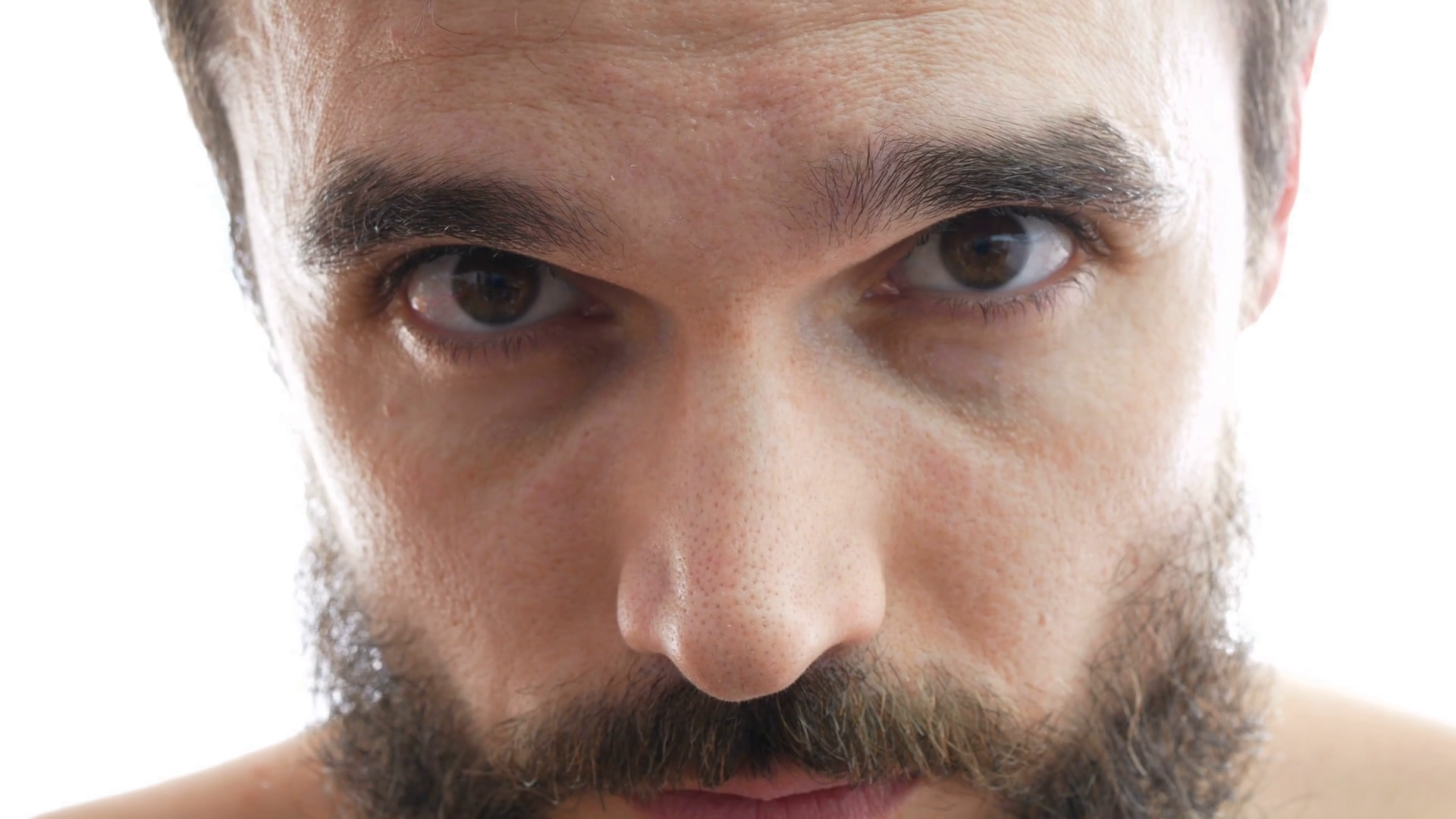 Close-up of serious bearded man face with brown eyes looking at you ...