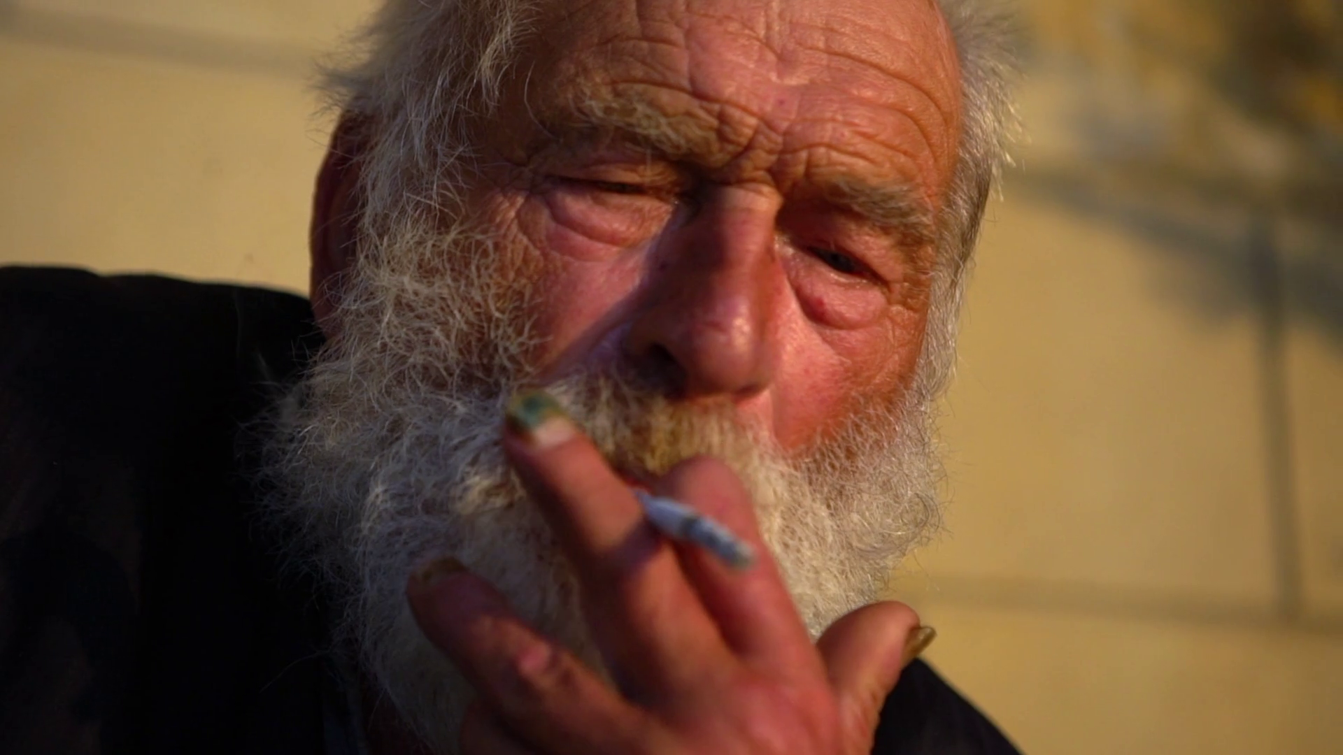 in slow motion closeup portrait of old white bearded man smoking ...