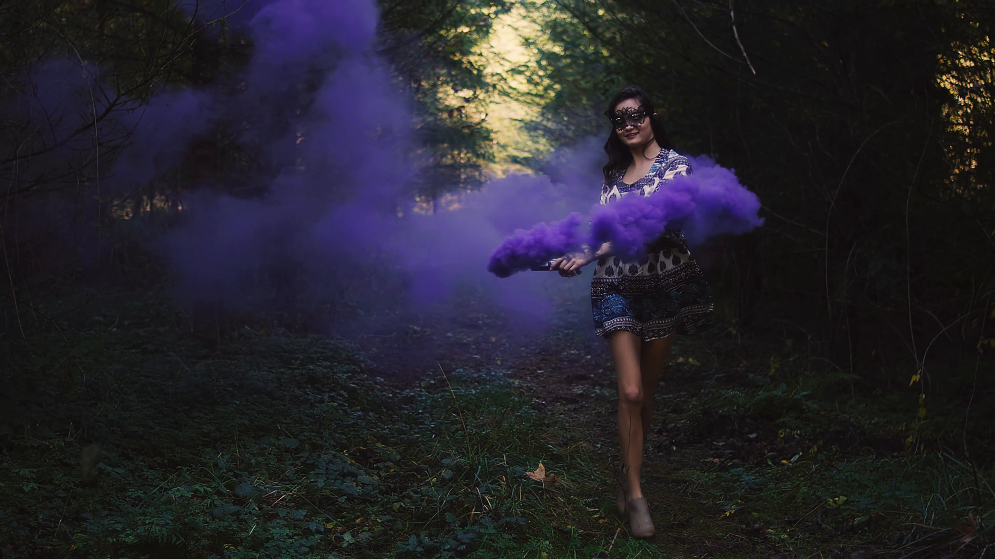 Beautiful girl in a dress spins around in purple smoke from a color ...