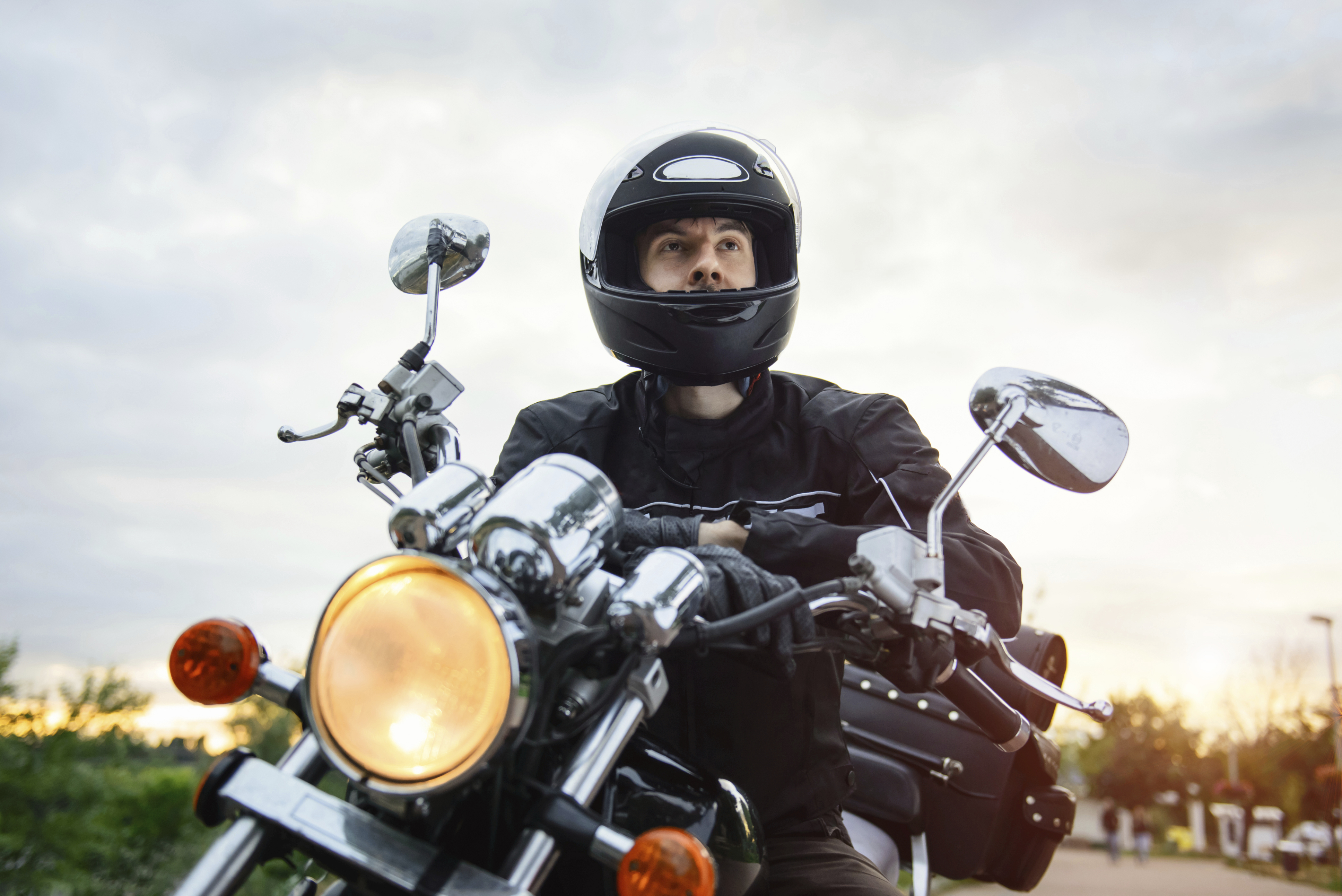 Biker in helmet driving motorcycle on sunset. - Tiemann Law Firm
