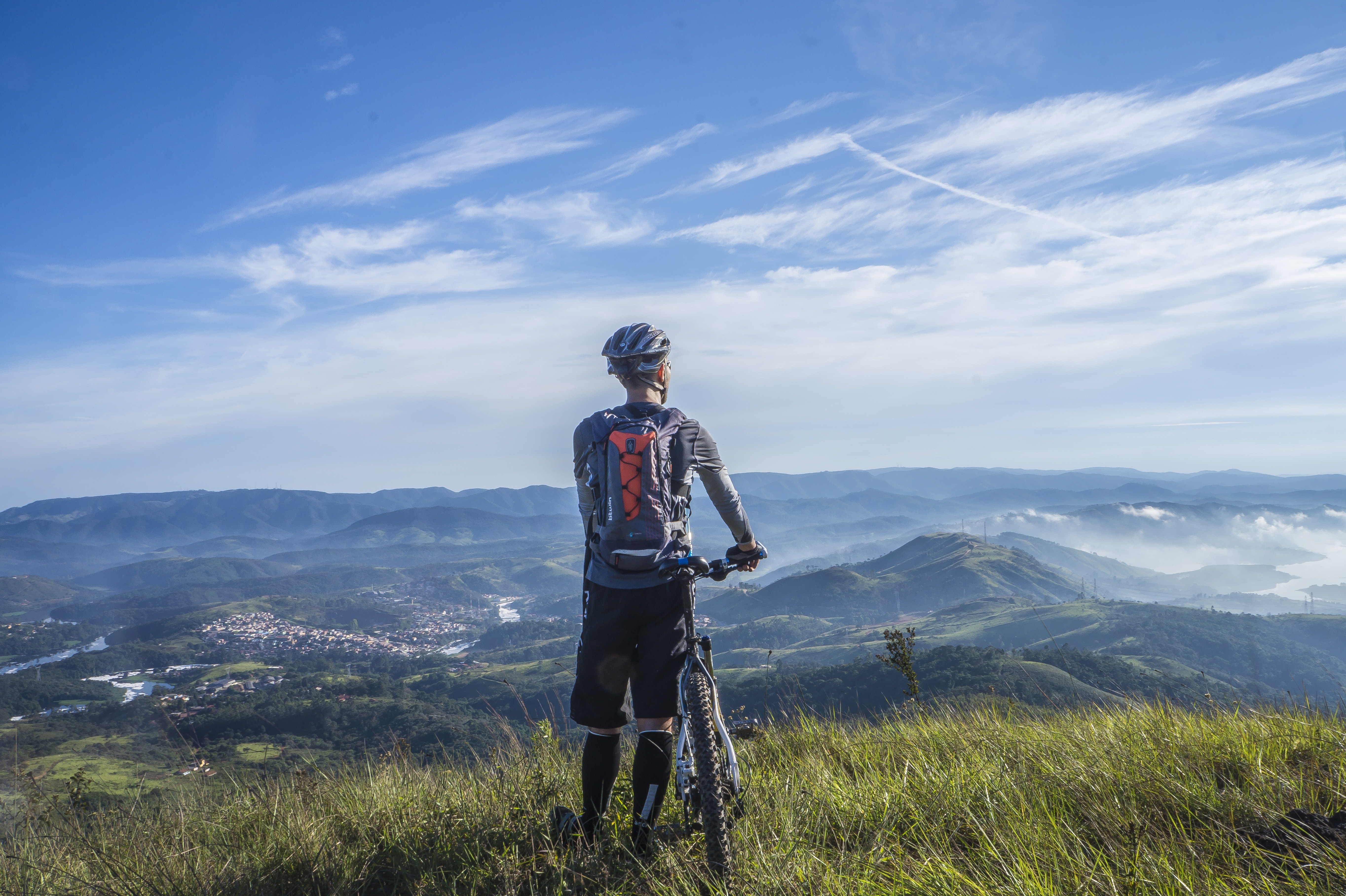 Biker holding mountain bike on top of mountain with green grass photo