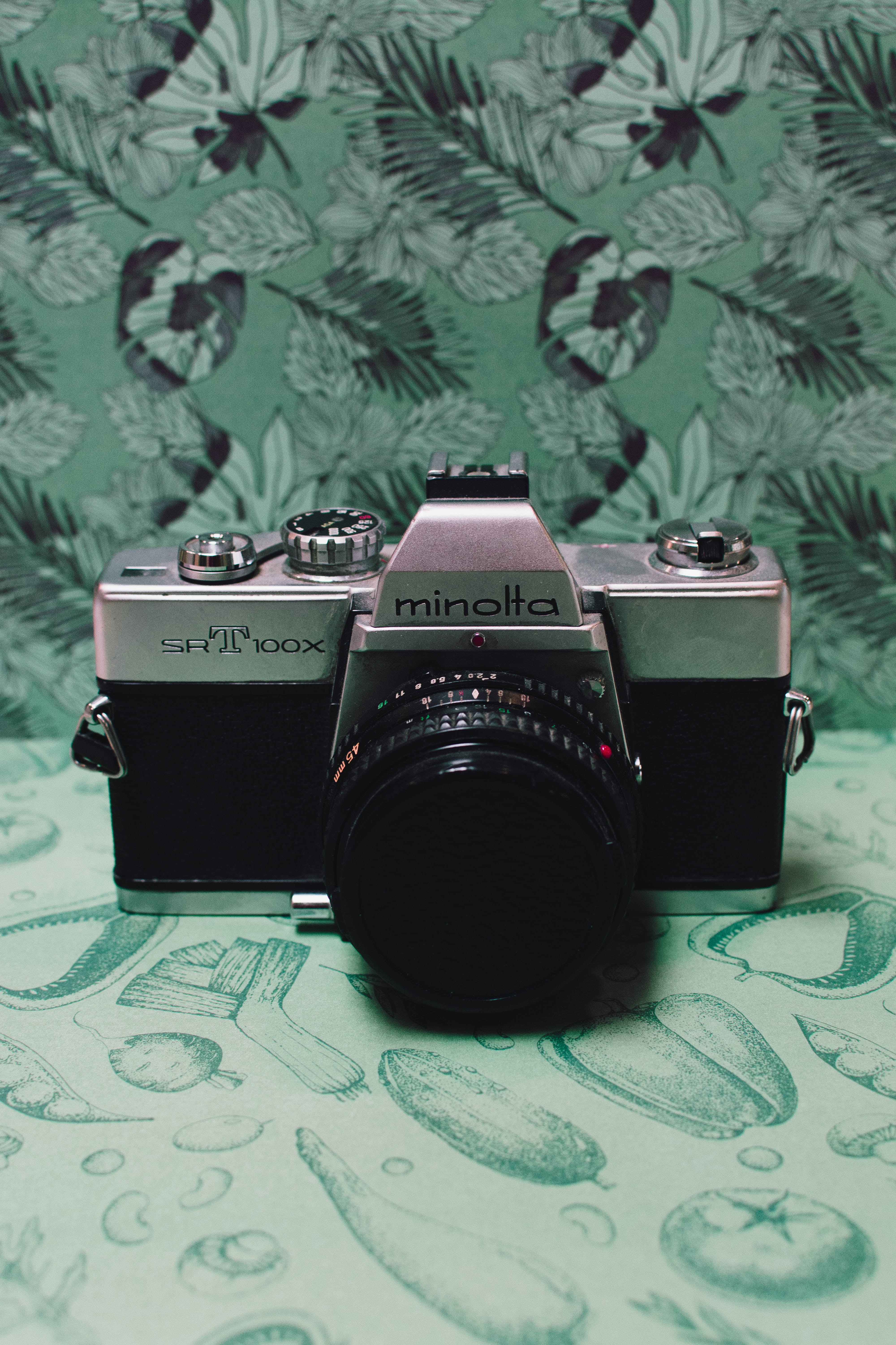 Black and gray film camera on green floral textile photo