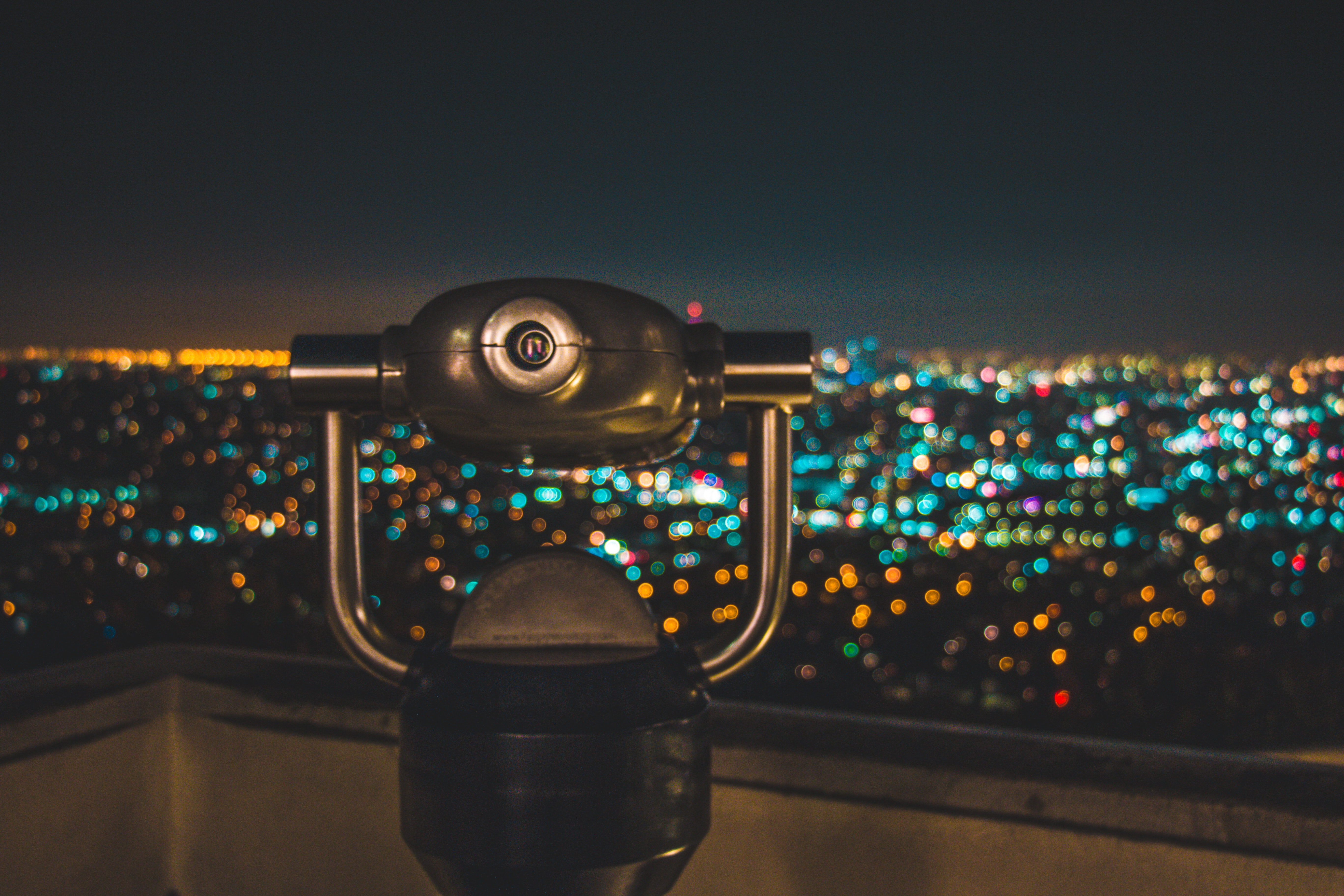 Black binocular facing lighted city at nighttime photo