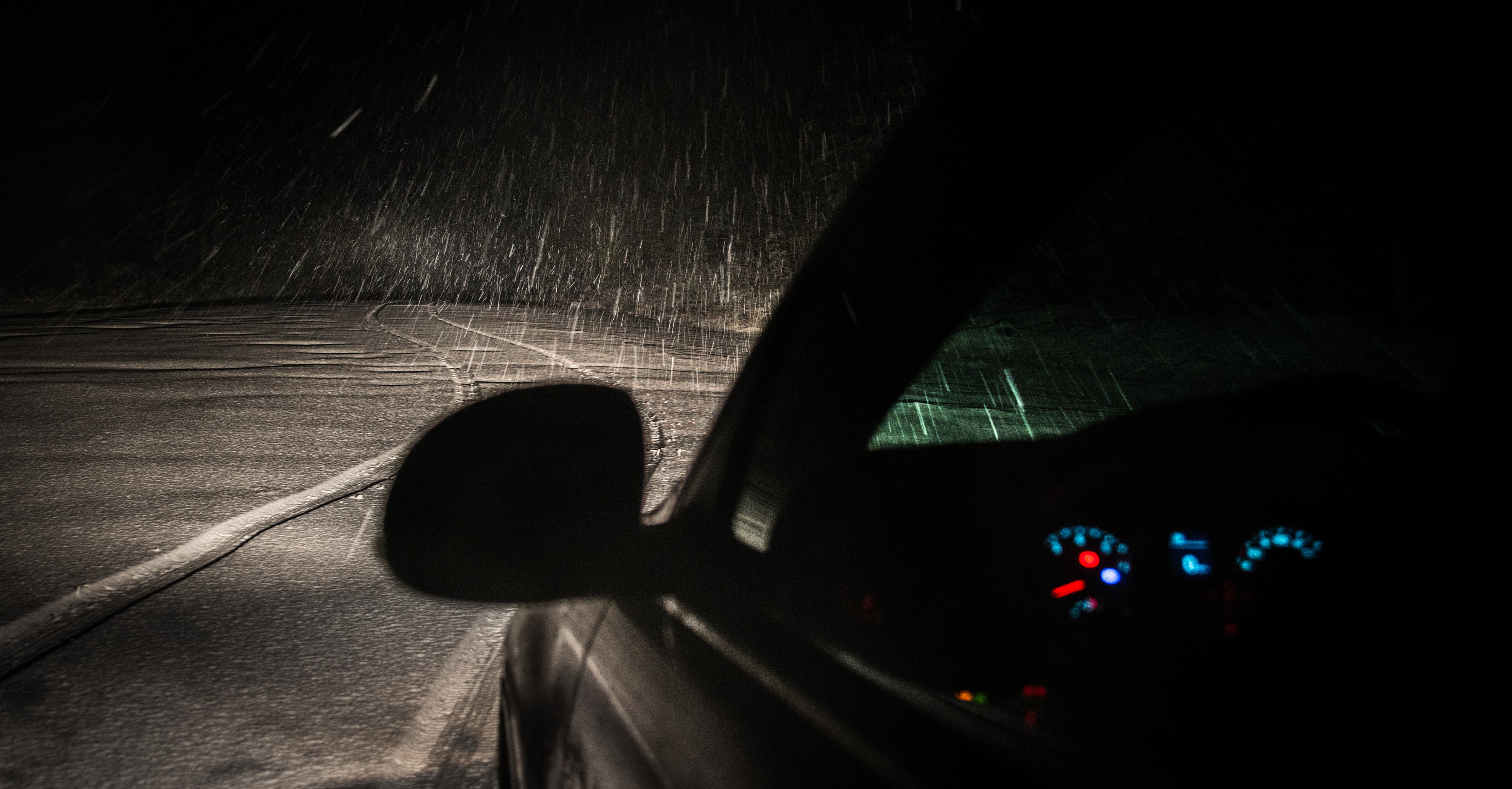 Black car on roadway while raining during nighttime photo