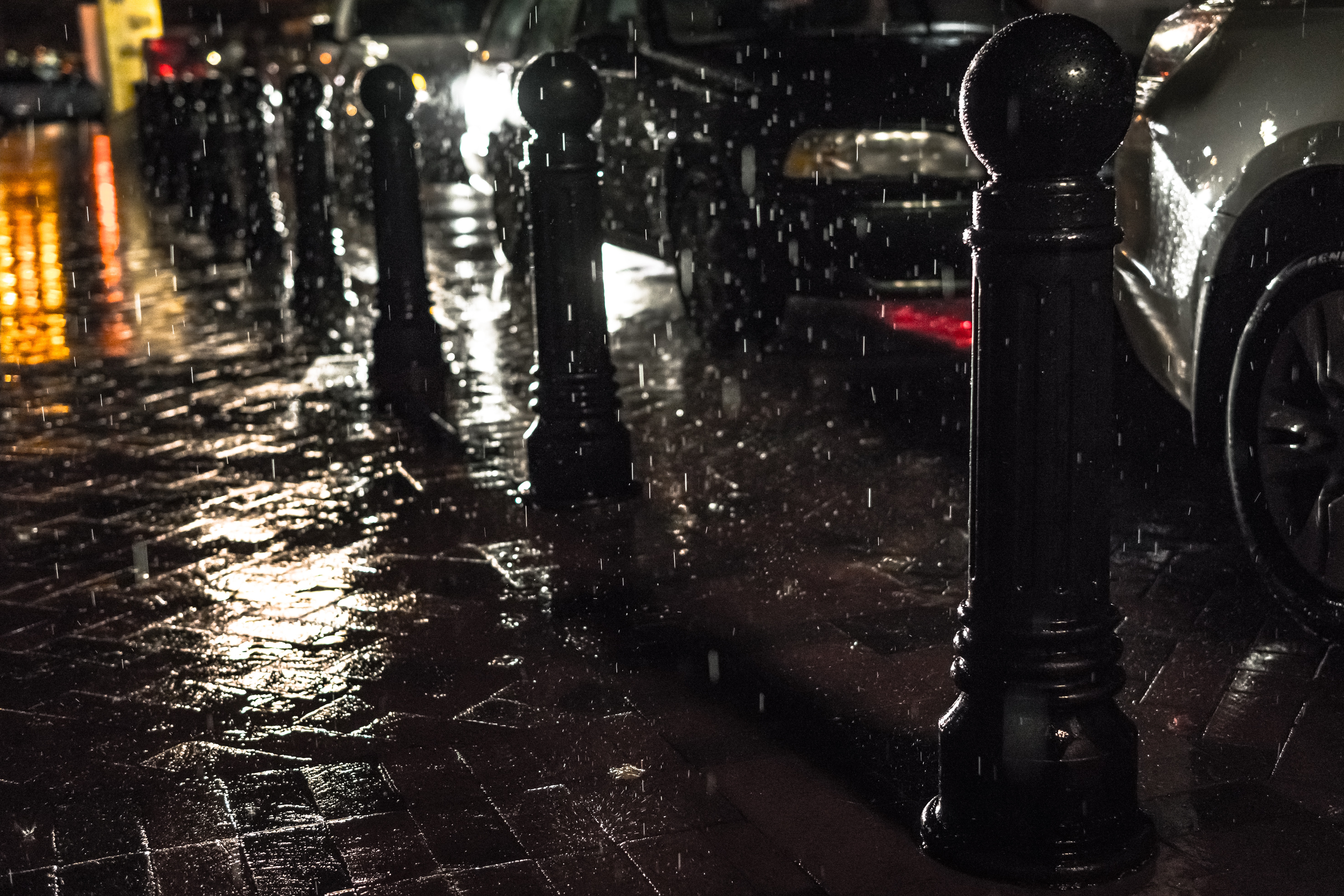 Black posts on black pavement beneath falling rain photo