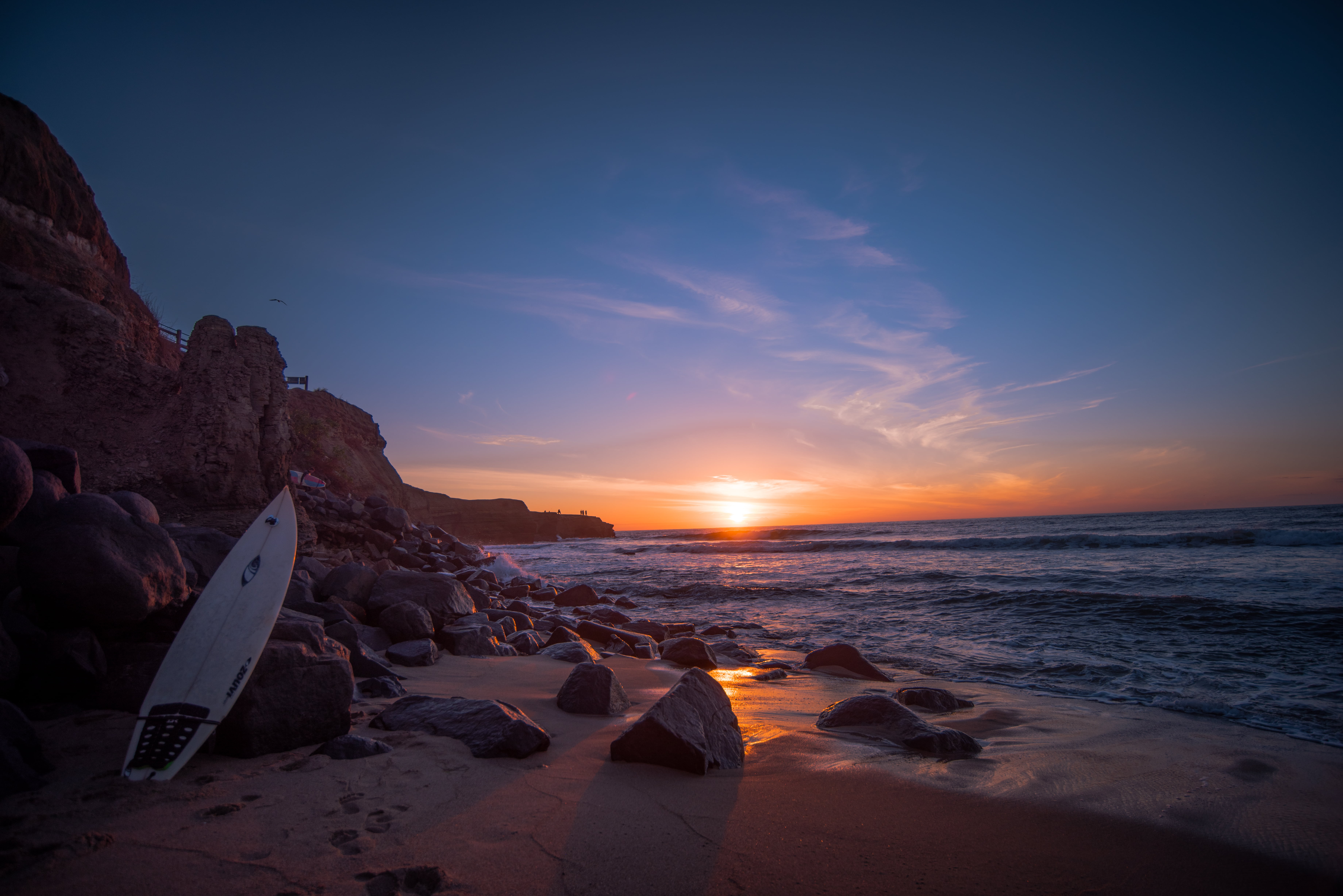 White surfboard leaning on rock near water at sunset HD wallpaper ...