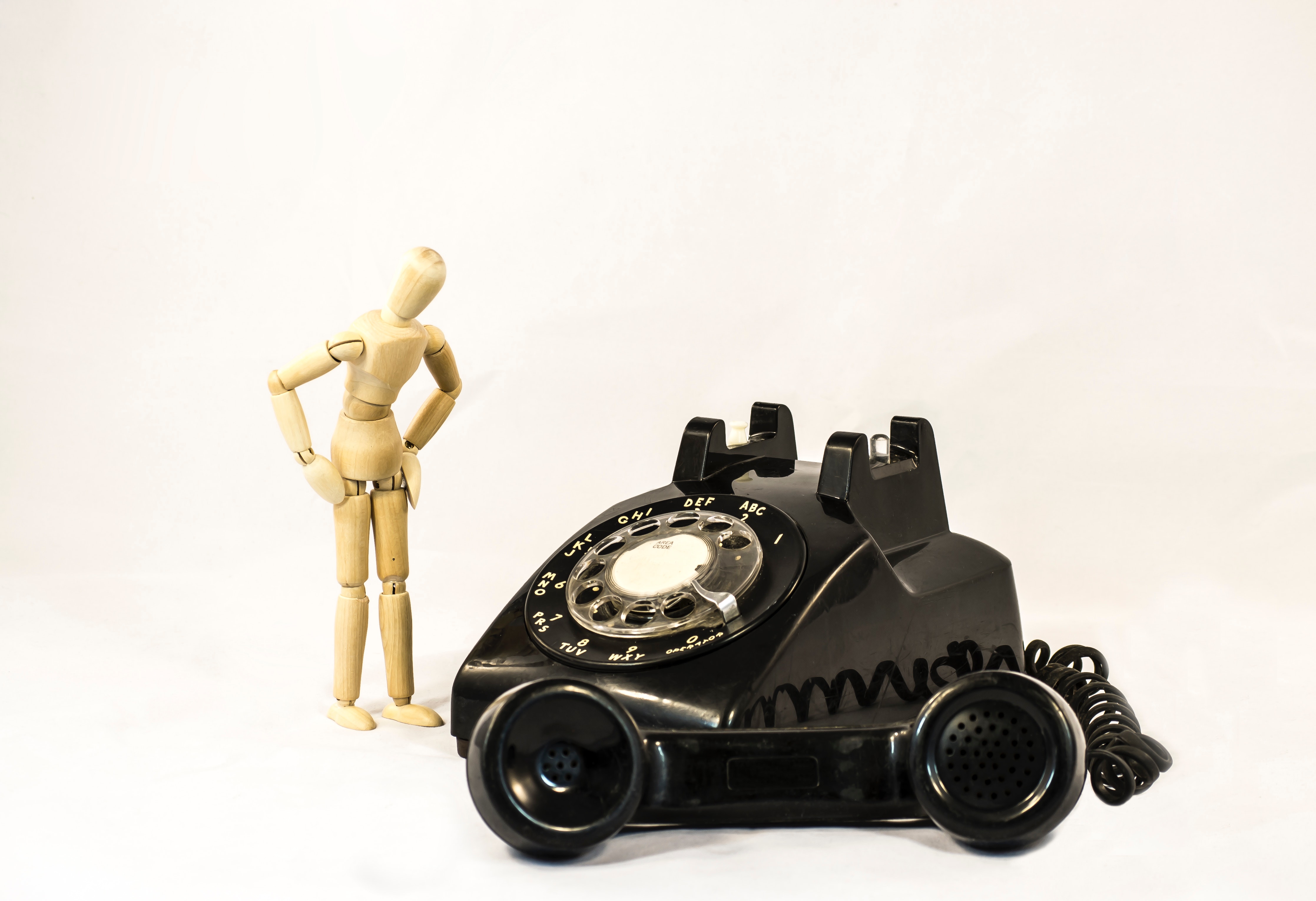 Black rotary telephone beside beige manekin photo