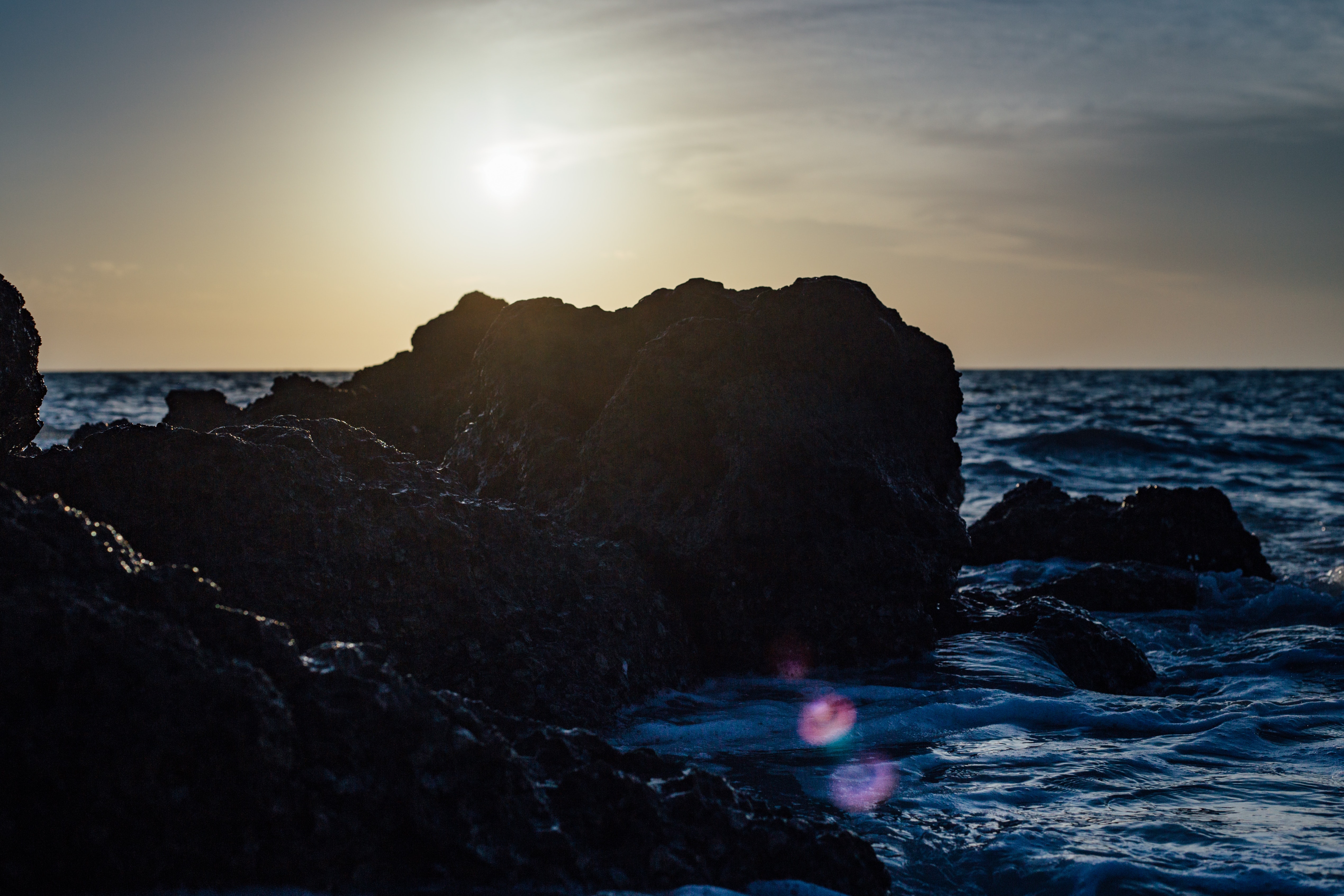 Black stones on sea side during sunset photo
