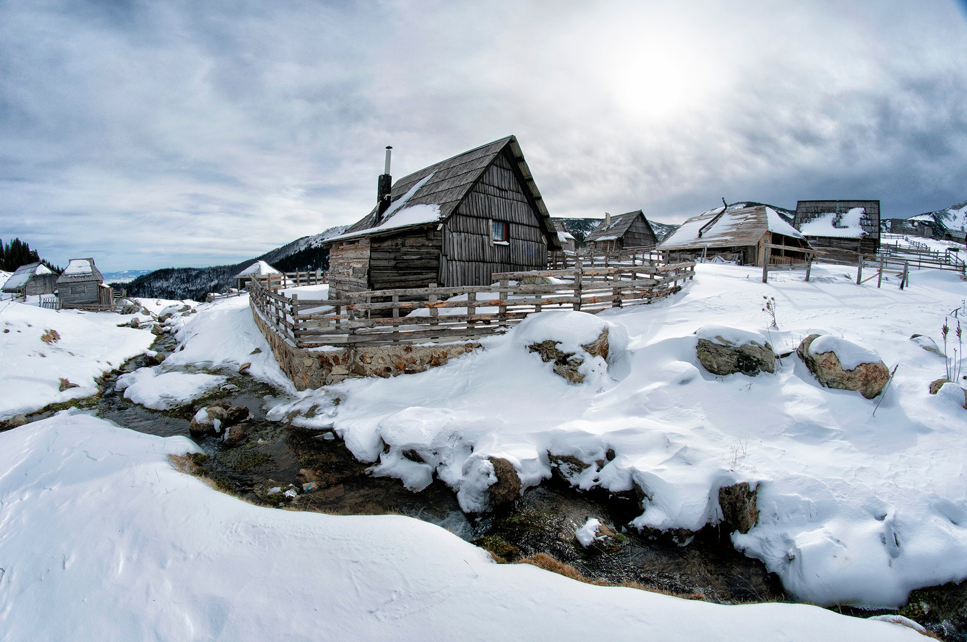 Black wooden house surrounded by snow under white clouds photo