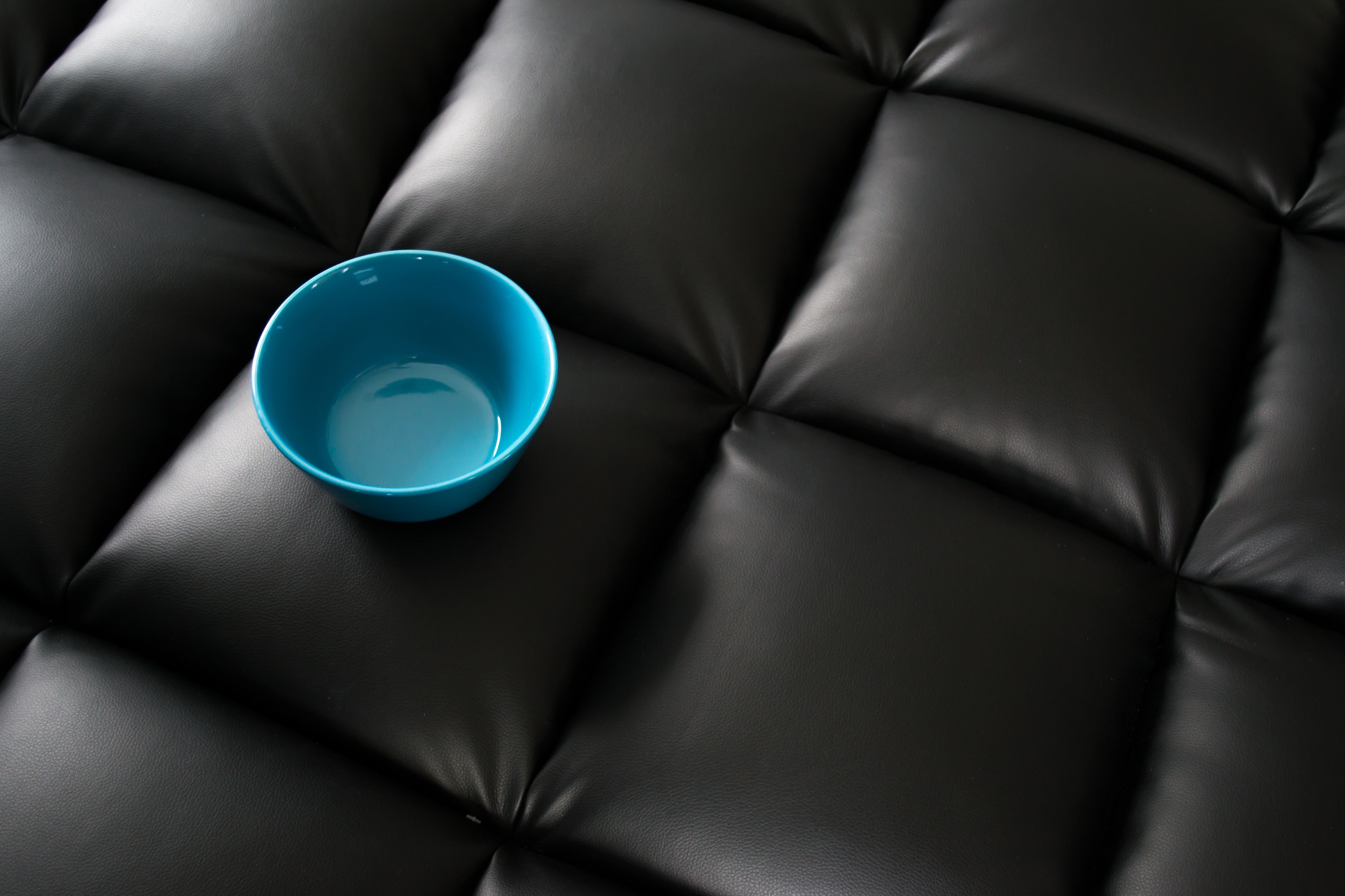 Blue ceramic bowl on black leather surface photo