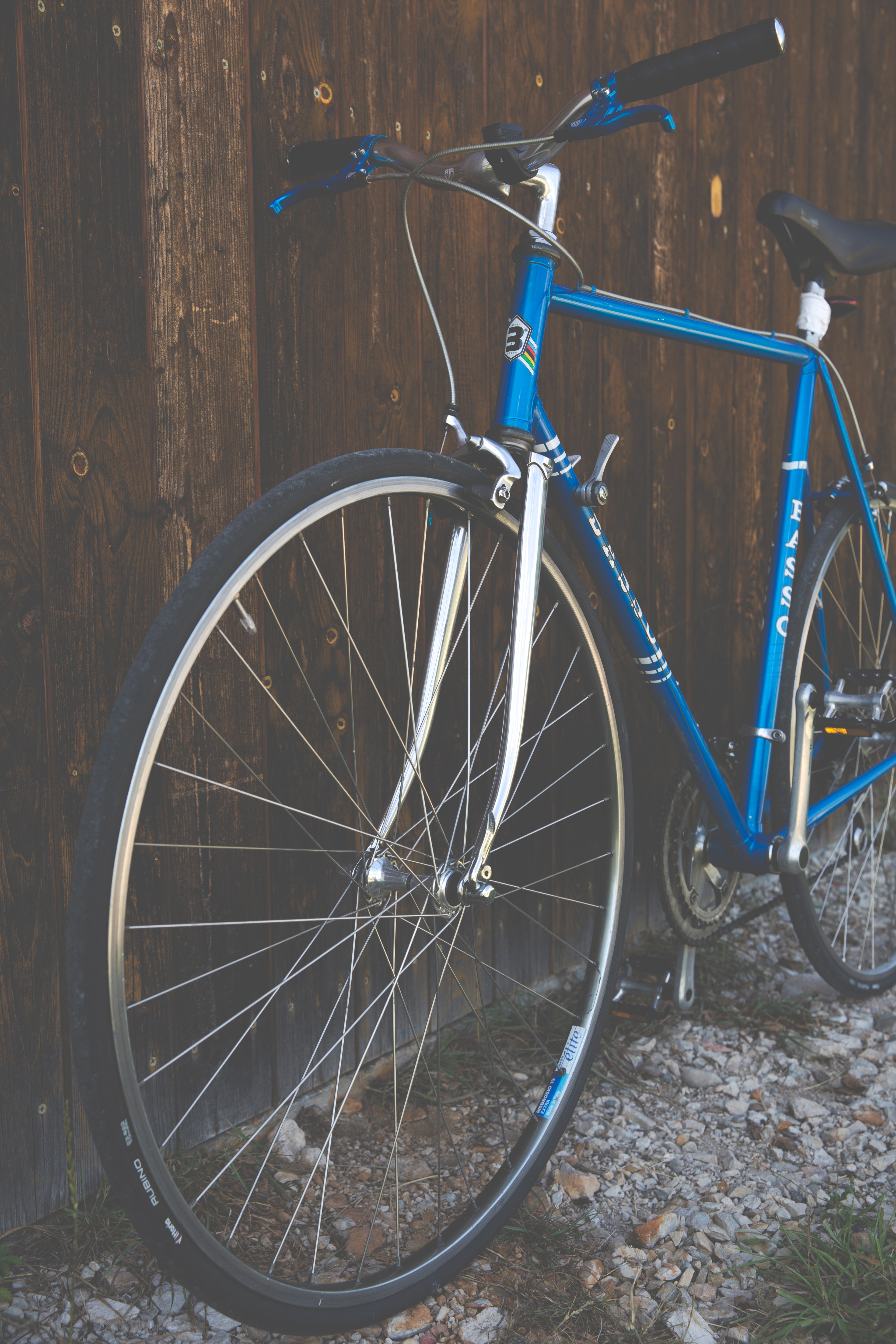 Blue city bike beside brown wooden fence photo