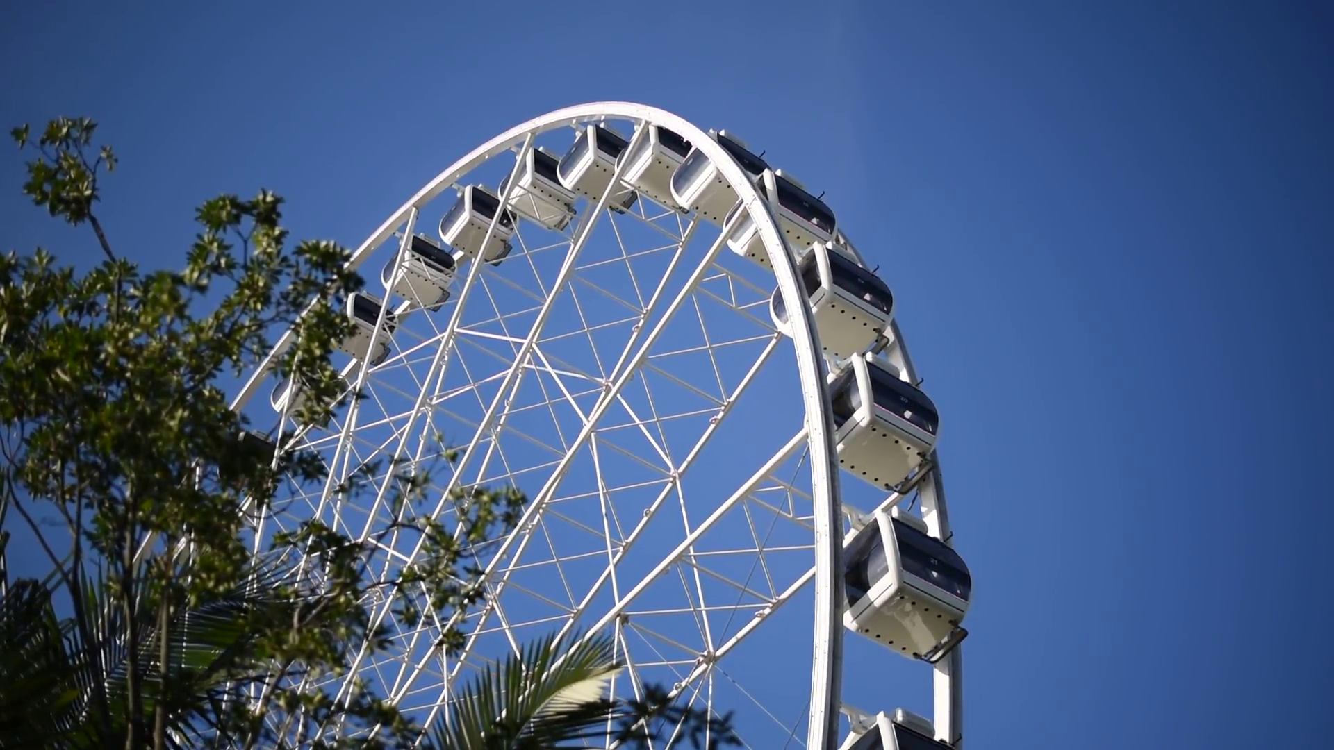 A side view of a big white Ferris wheel on a blue sky without cloud ...