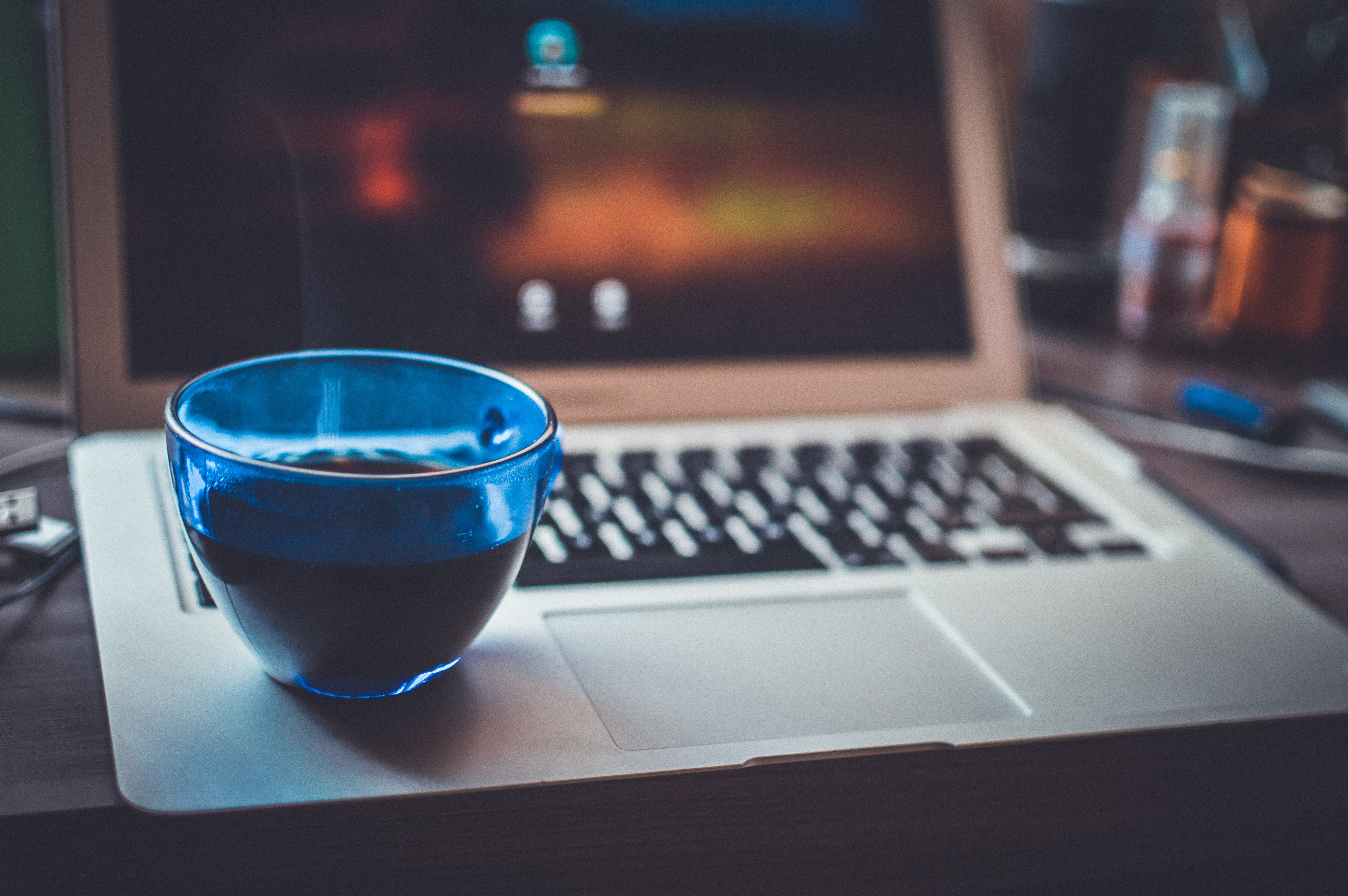 Blue glass cup on silver laptop computer photo