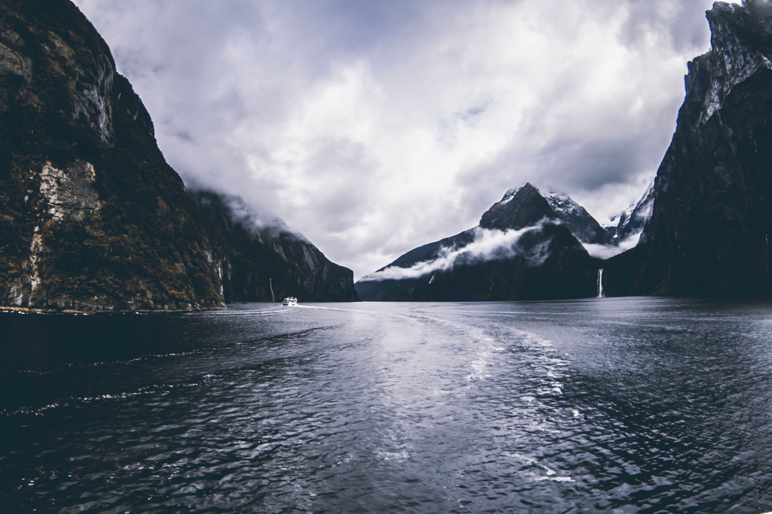 Body of water surround by mountains under cloudy sky photo