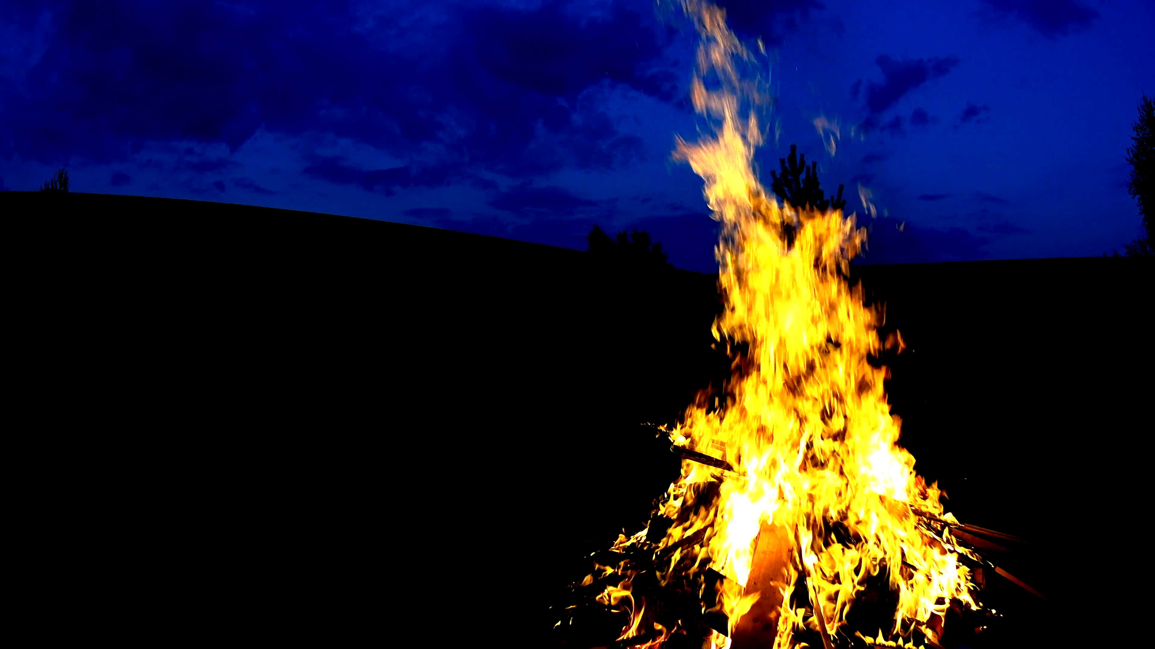 Man silhouette throwing firewoods to bonfire, dark background ...