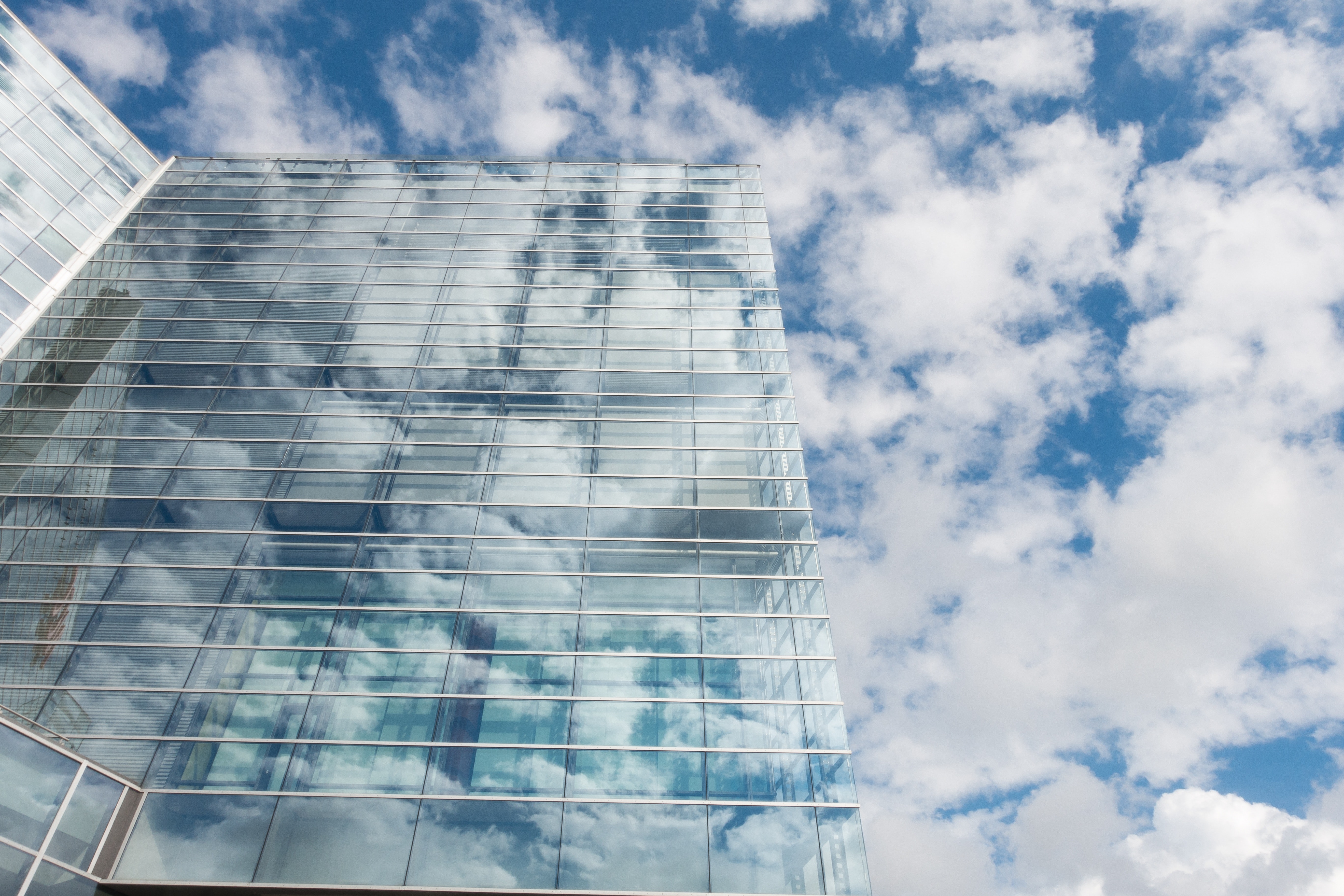 Bottom view of clear glass building under blue cloudy sky during day time photo