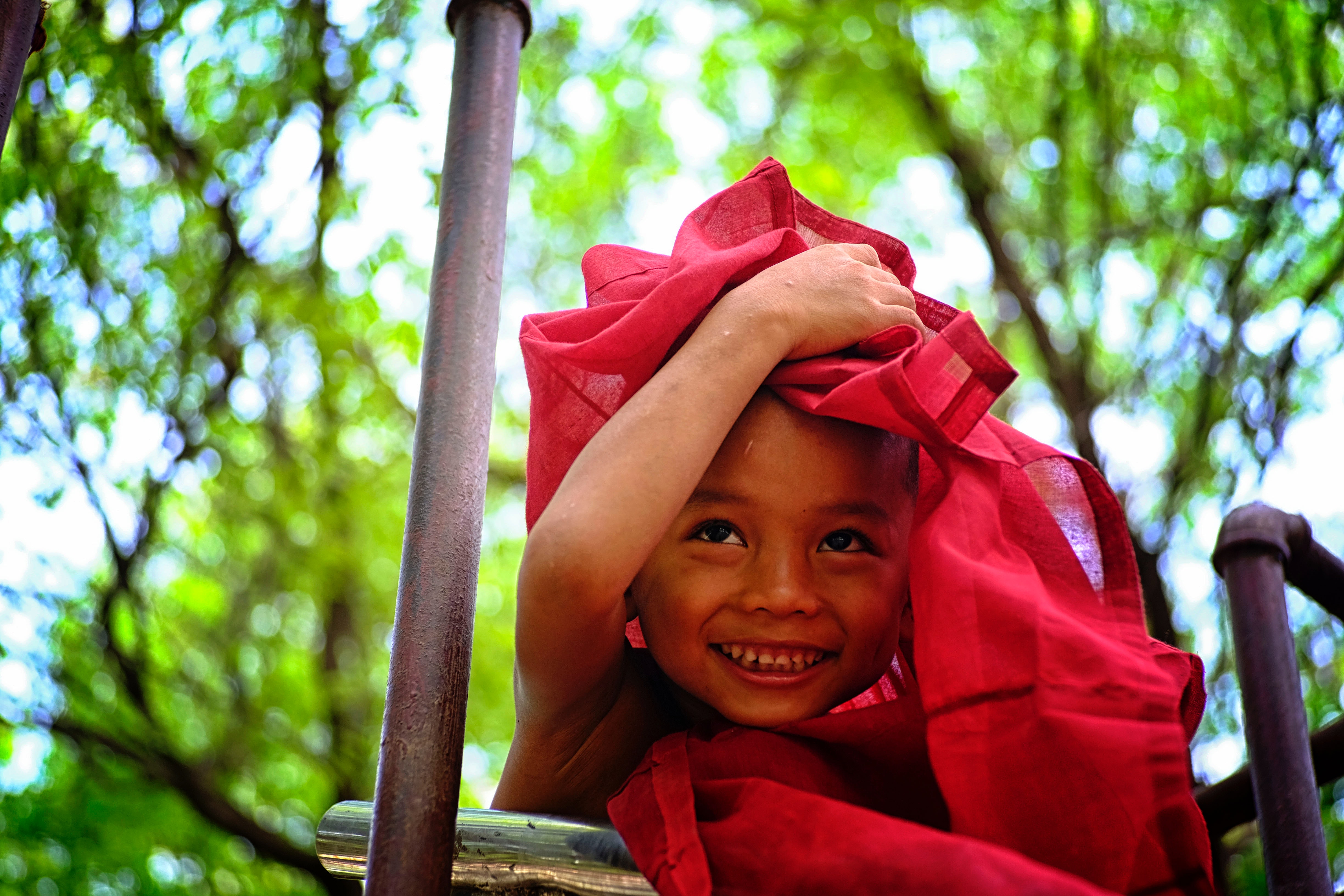 Boy holding red textile covering his head photo