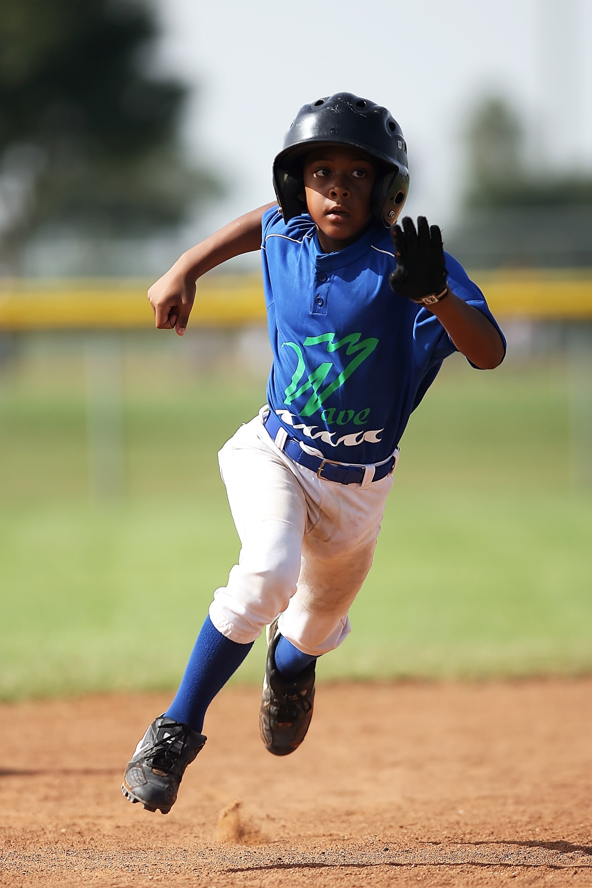 Boy in blue and white baseball jersey running on brown soil field during daytime photo
