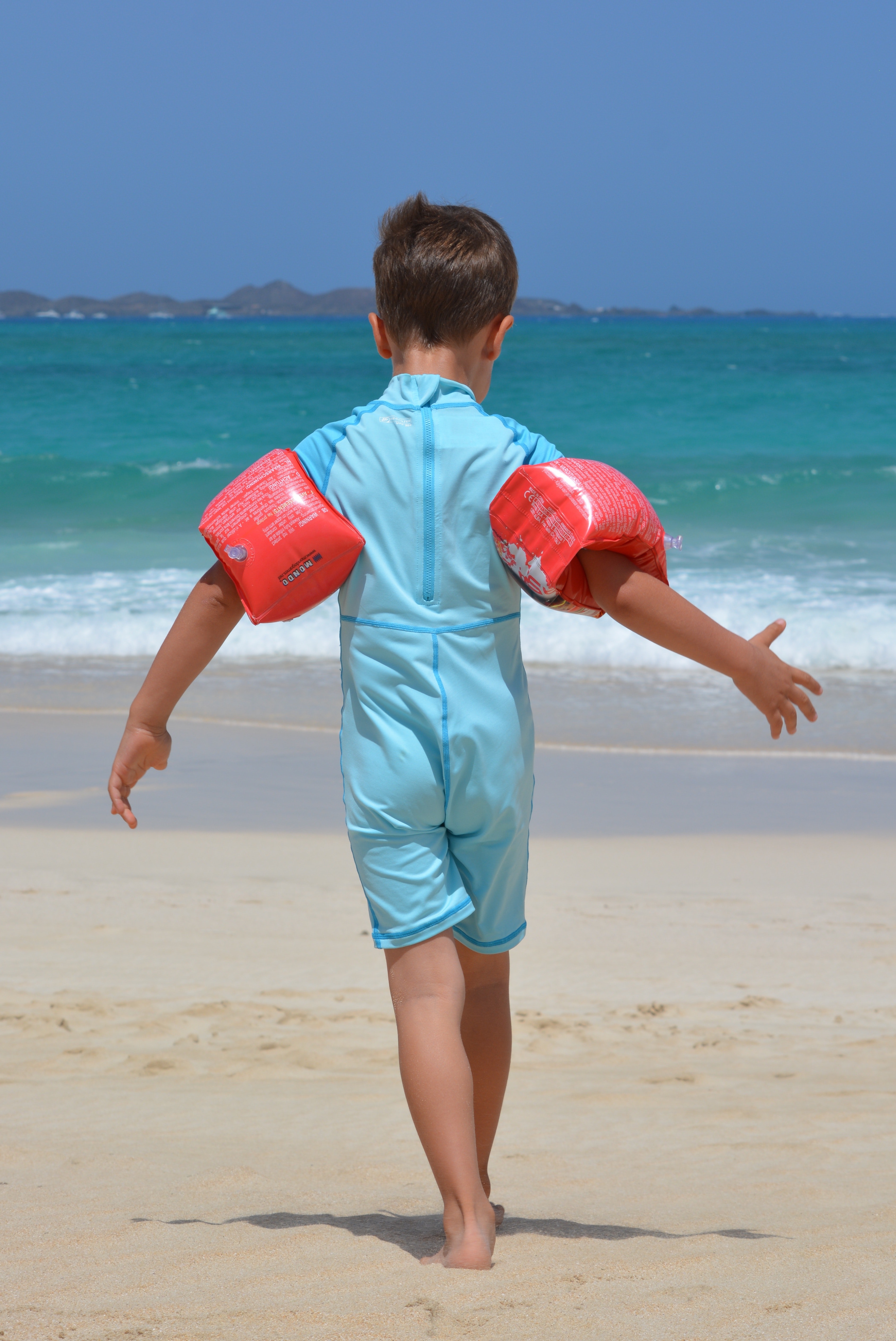 Boy on blue onesie on beach during day photo