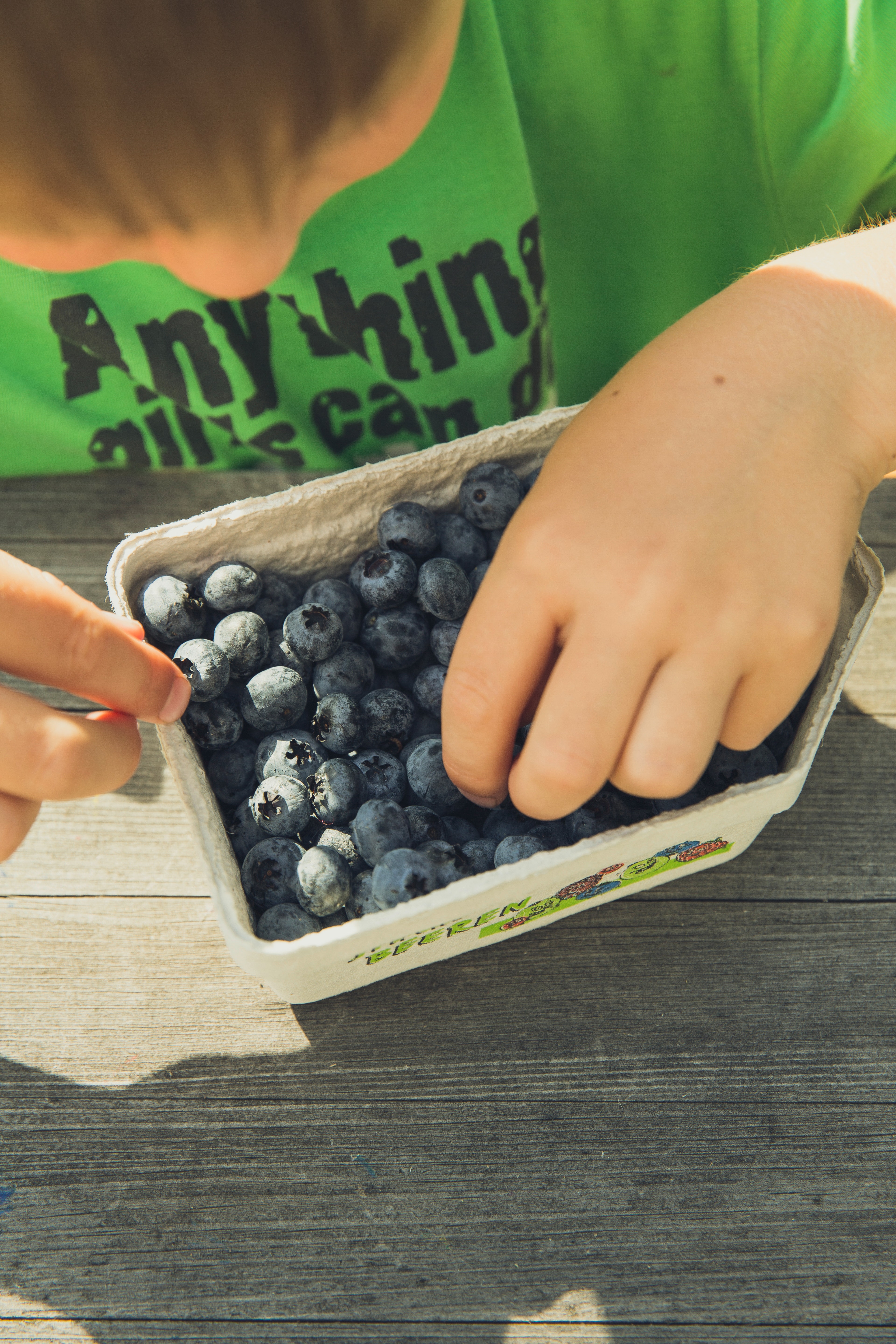 Boy picking on blueberries in cardboard box photo