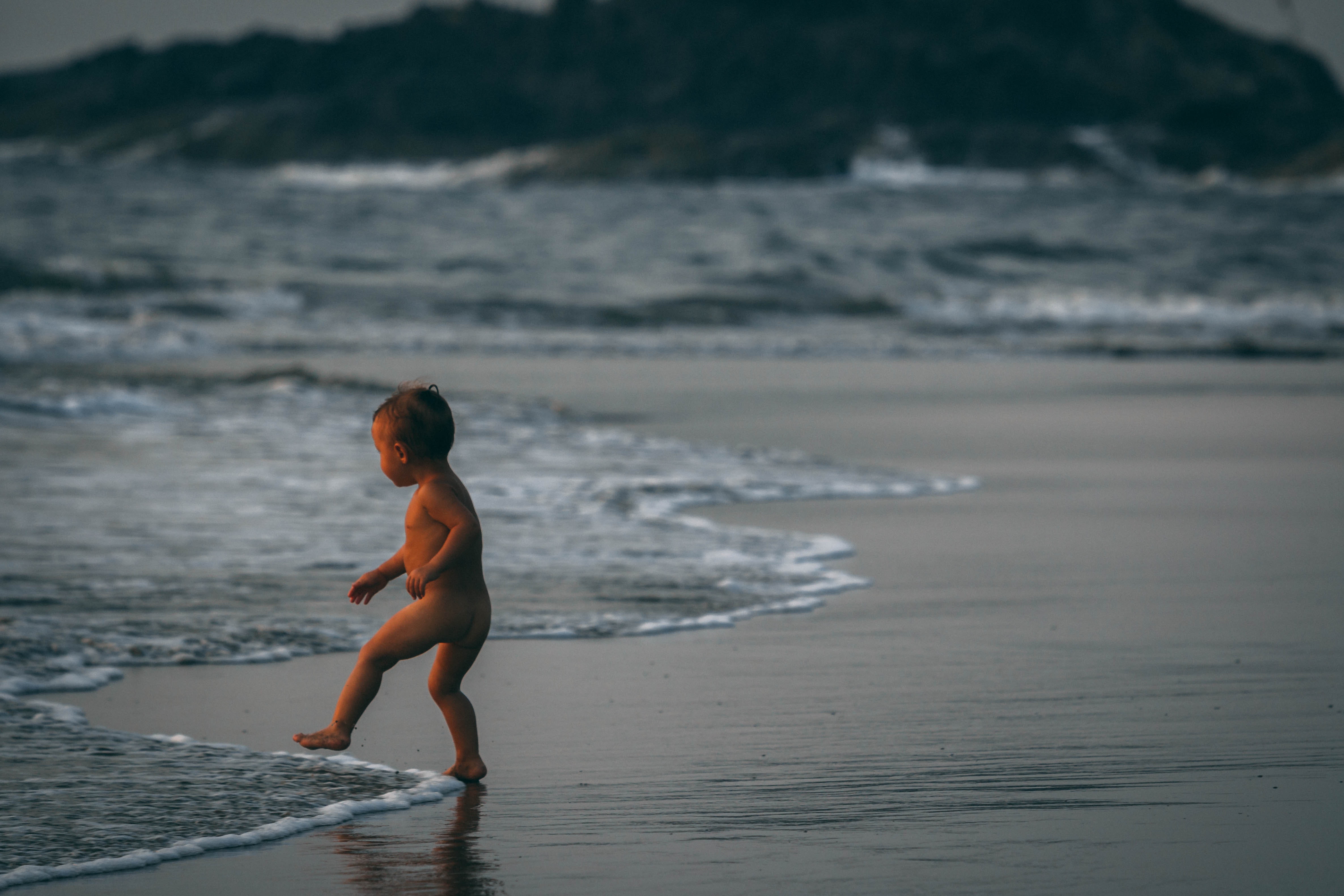 Boy standing beside seashore waves photo