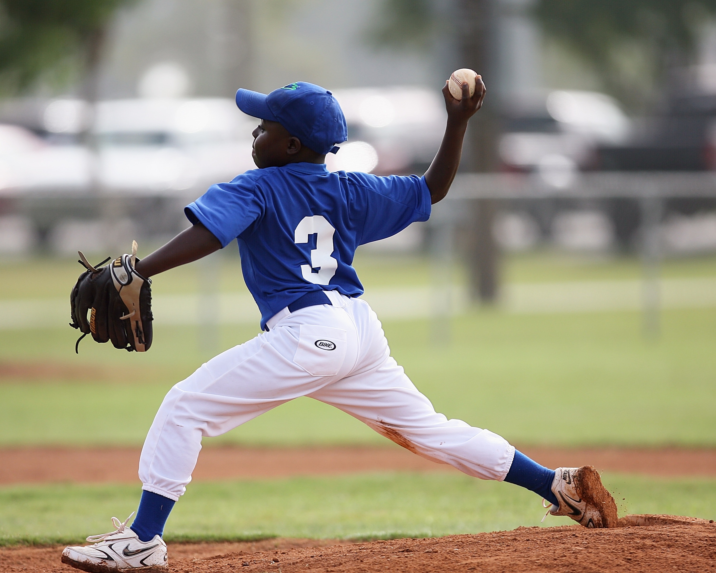 Boy wearing blue and white 3 jersey about to pitch a baseball photo