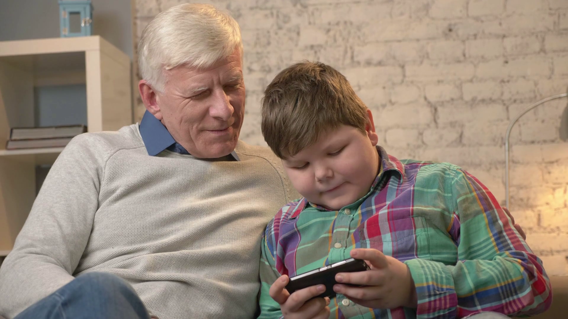 Grandfather and grandson sitting on the sofa using a smartphone ...