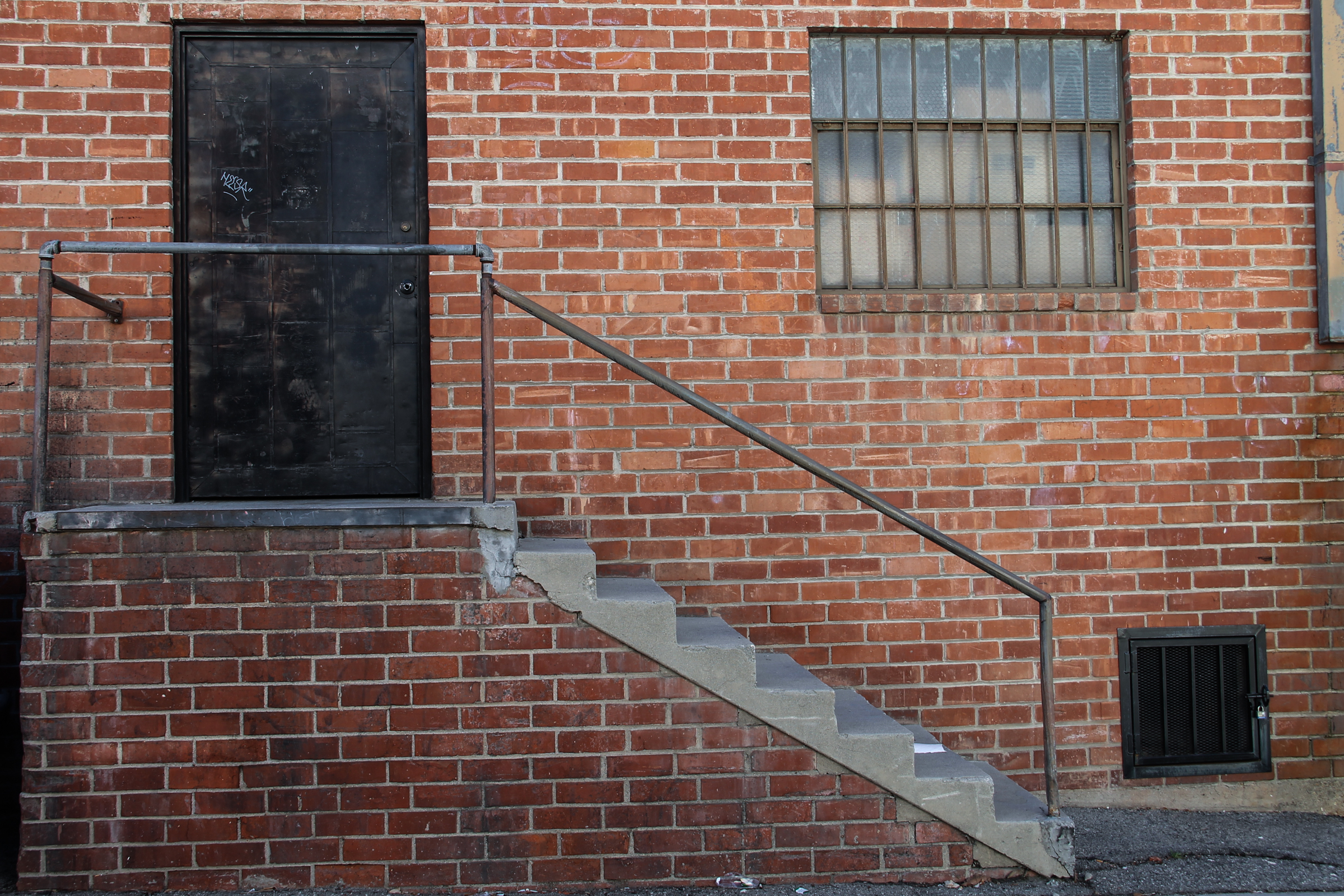 Free Stock Photo of Black Door & Staircase on Brick Building