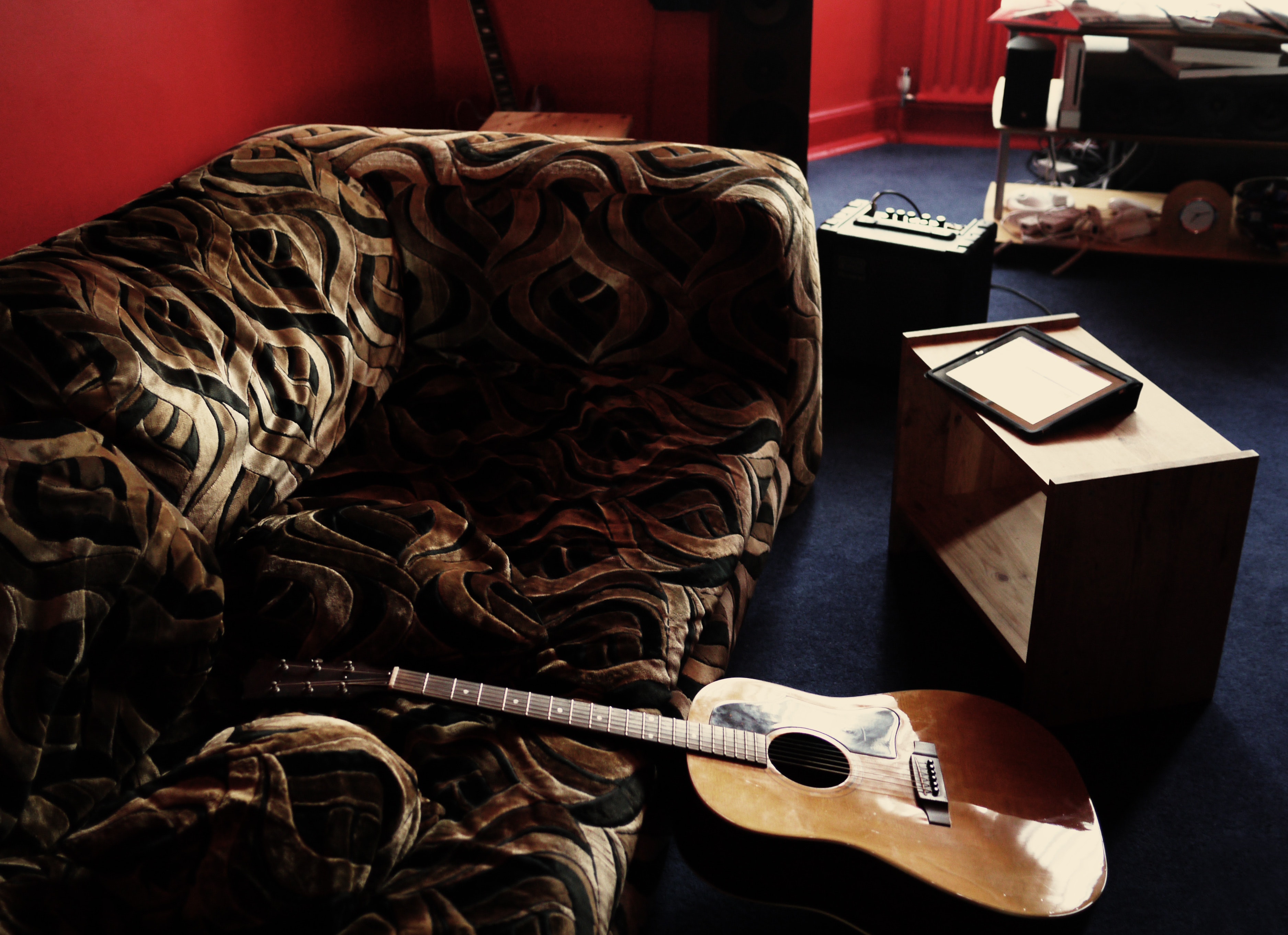 Brown acoustic guitar leaning on brown velvet couch photo