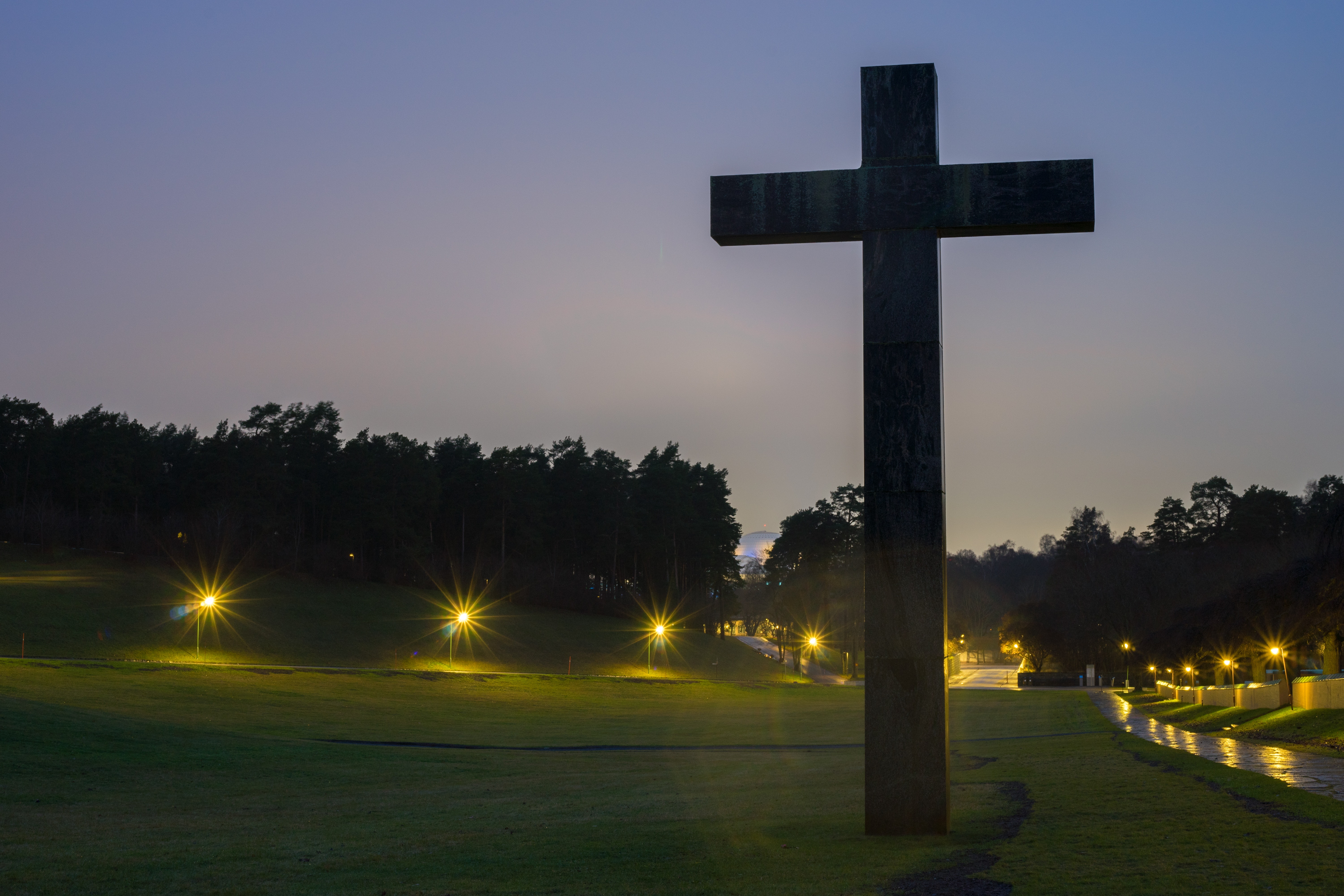 Brown cross statue on green grass field with turned on light during nighttime photo
