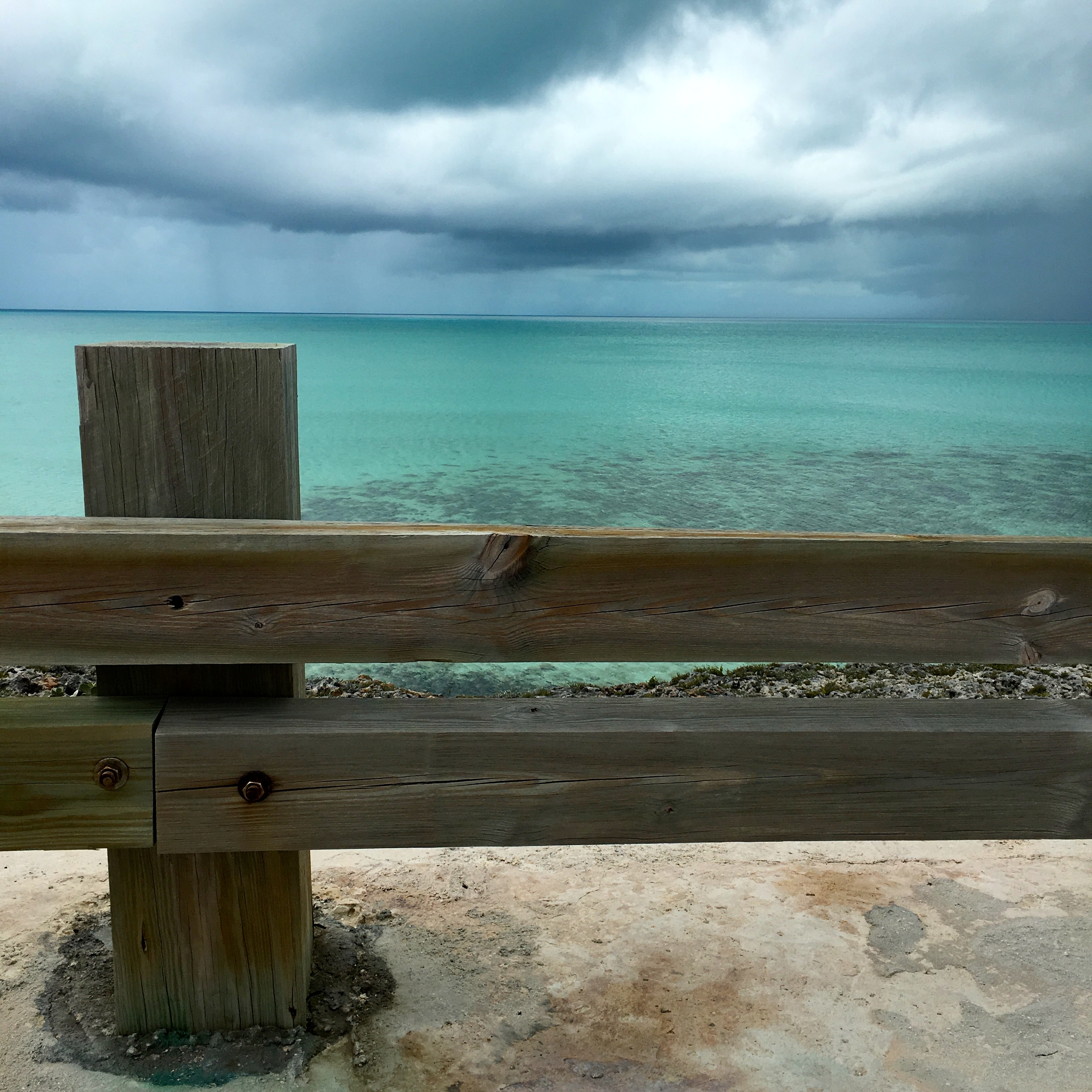 Brown wooden fence near blue ocean water under white cloudy sky during daytime photo