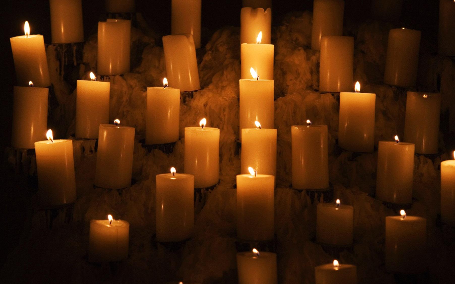 Rows Of Burning Candles Surrounded By Melted Candle Wax |