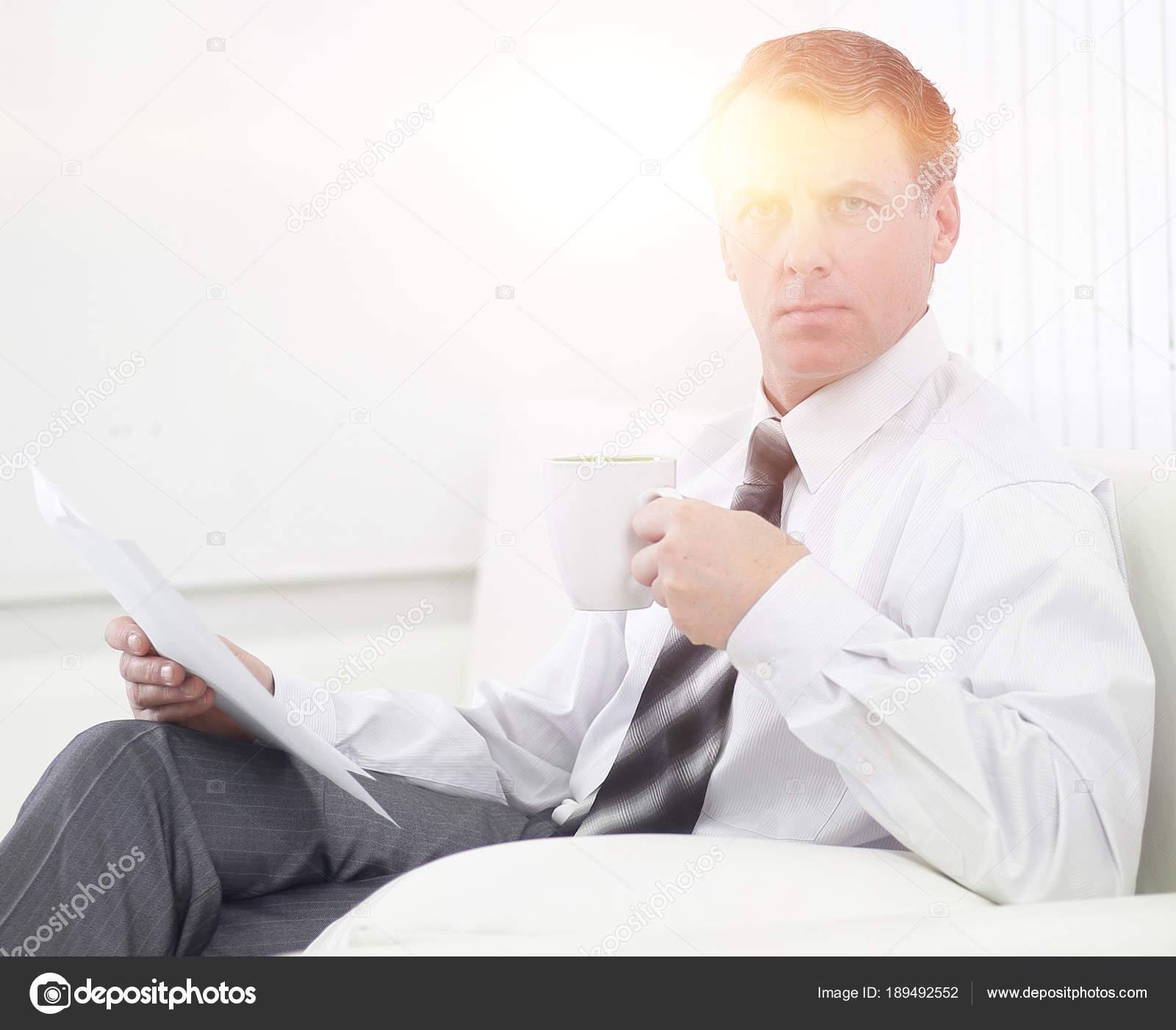 confident businessman drinking tea and reading a document,sitting in ...