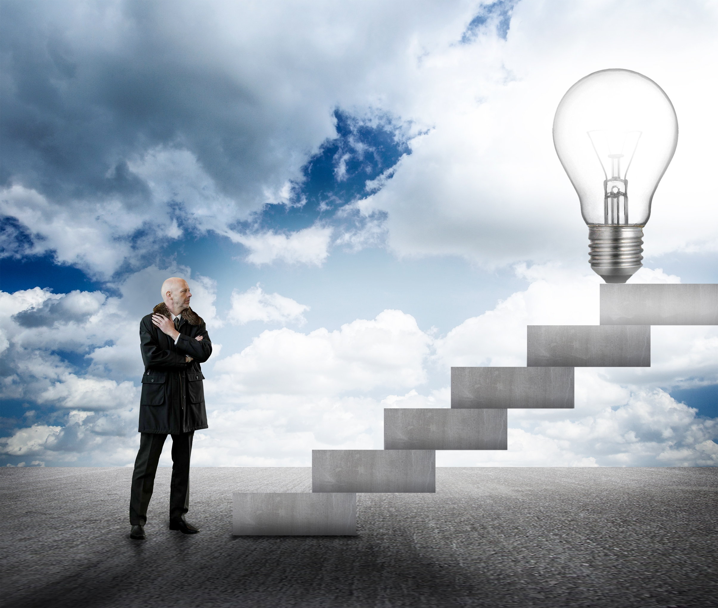 Businessman facing stairs with lightbulb photo