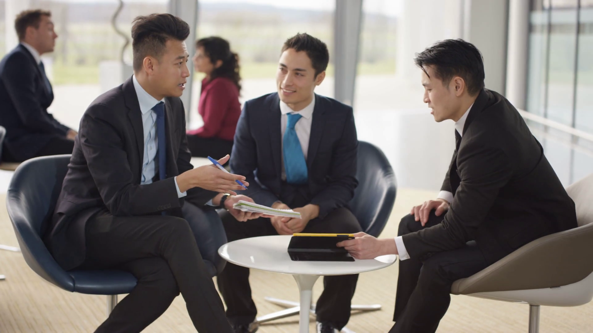 4K Asian businessmen in discussion in busy meeting area of modern ...
