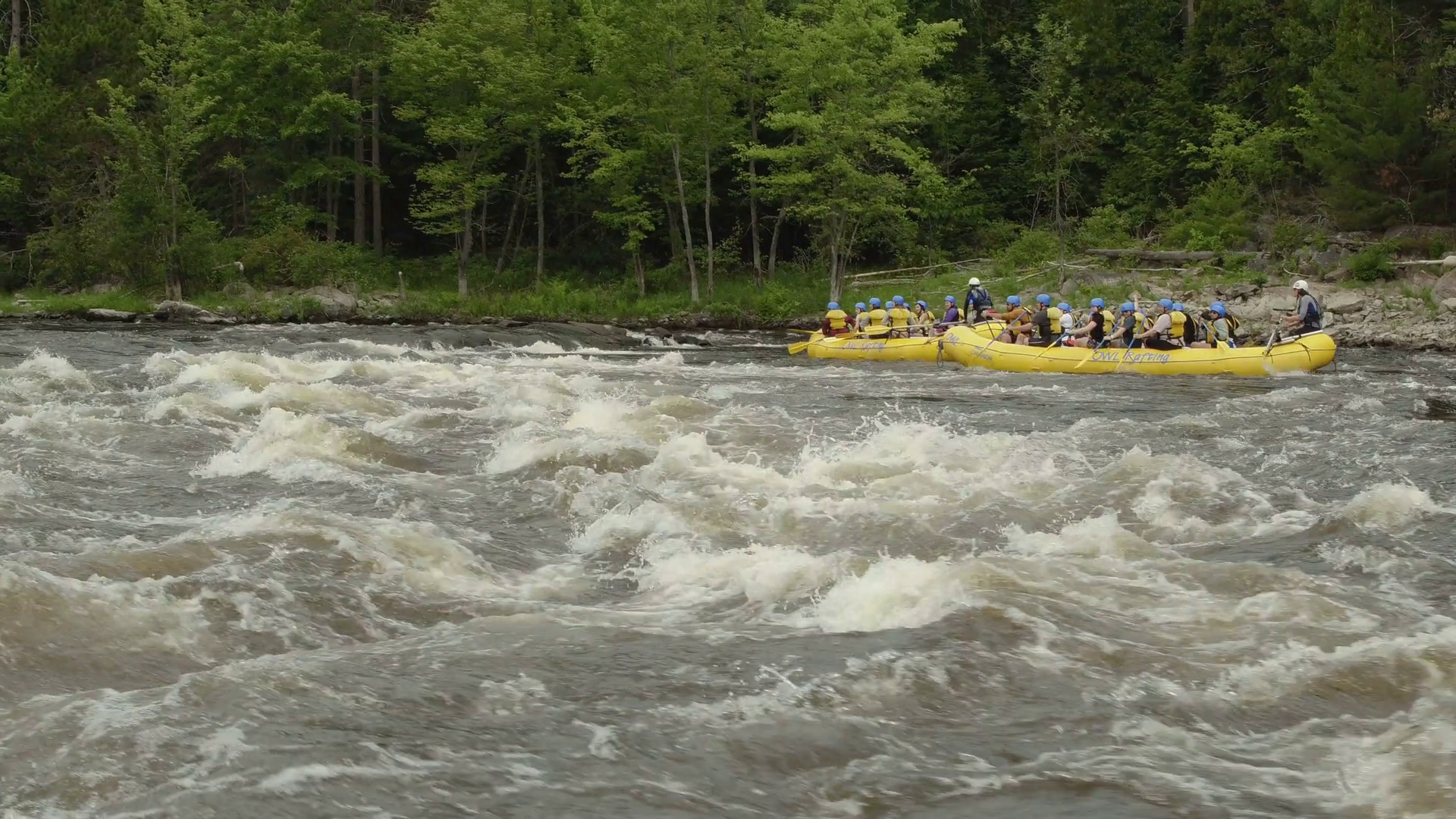 Aerial - Whitewater rafting on wide river rapids with big waves ...