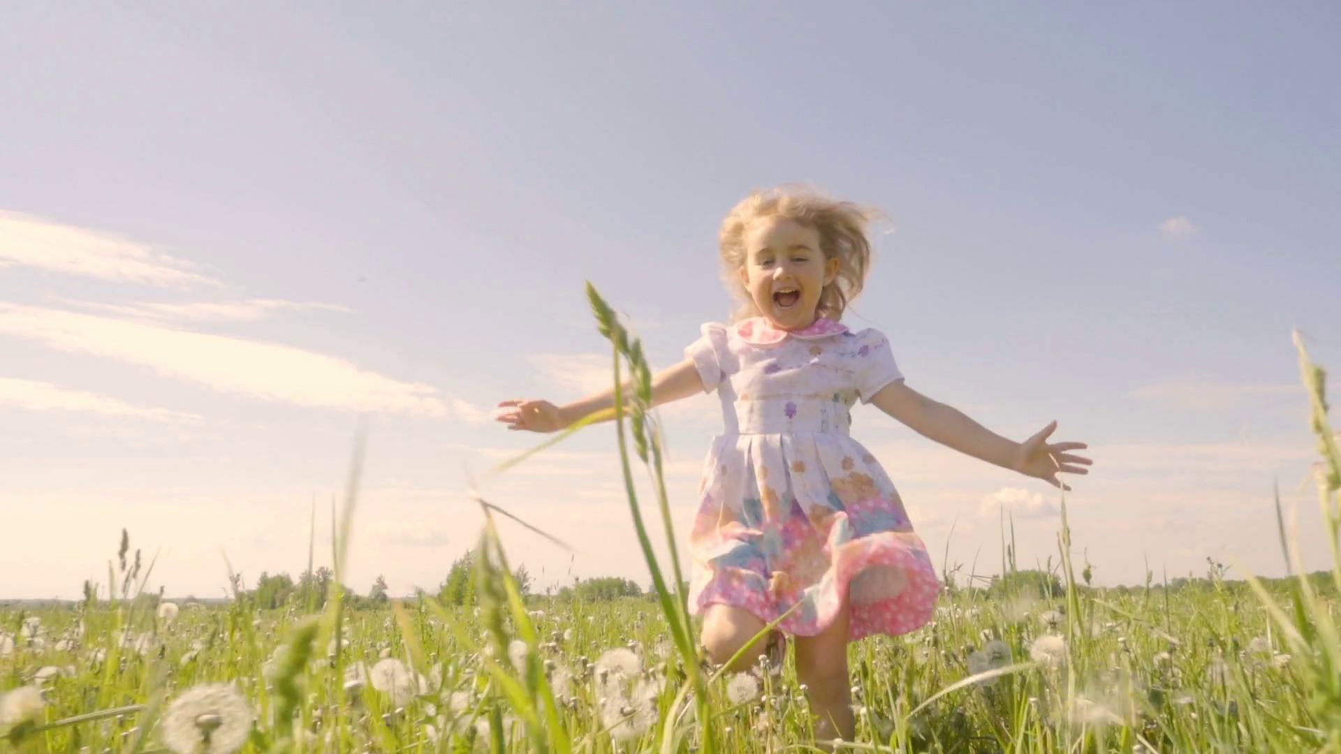 Cute little girl running in a meadow in the colors of a dandelion ...