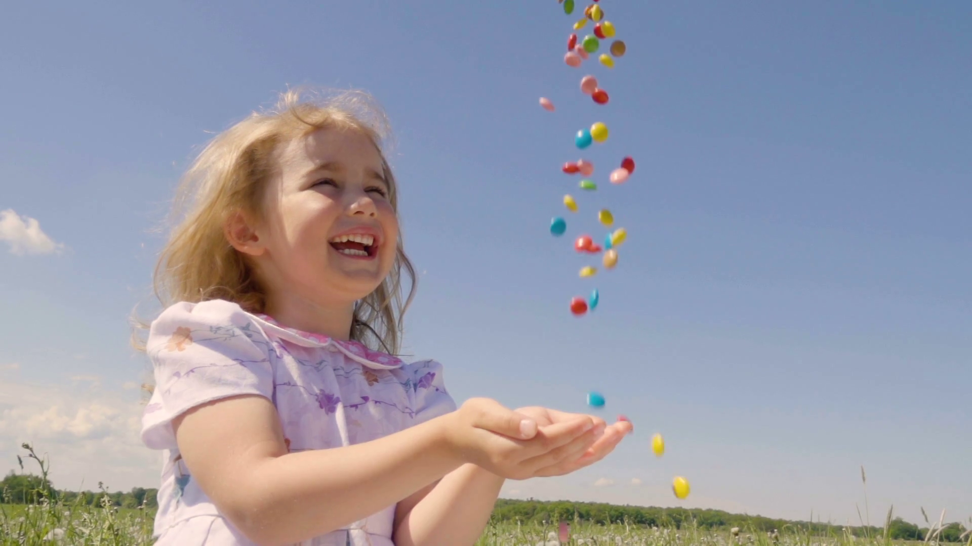 Cute little girl with pleasure catches multicolored candy falling ...