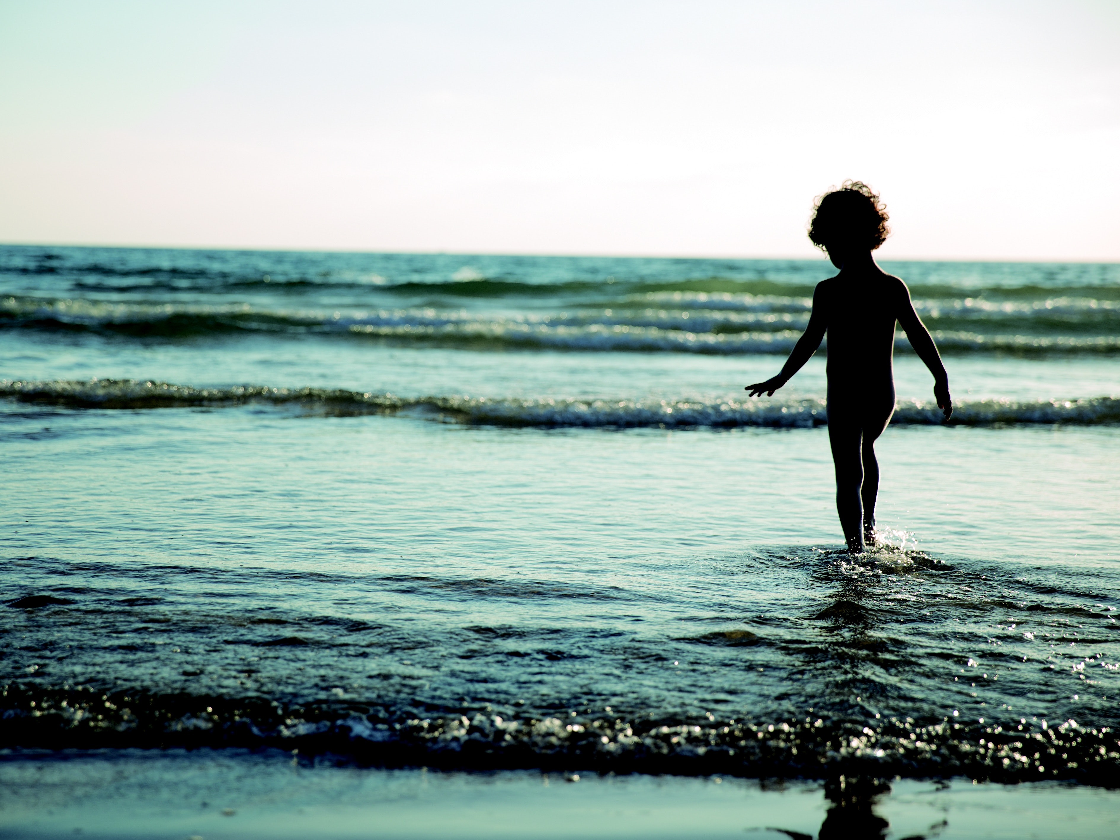 Child walking on seashore during daytime photo