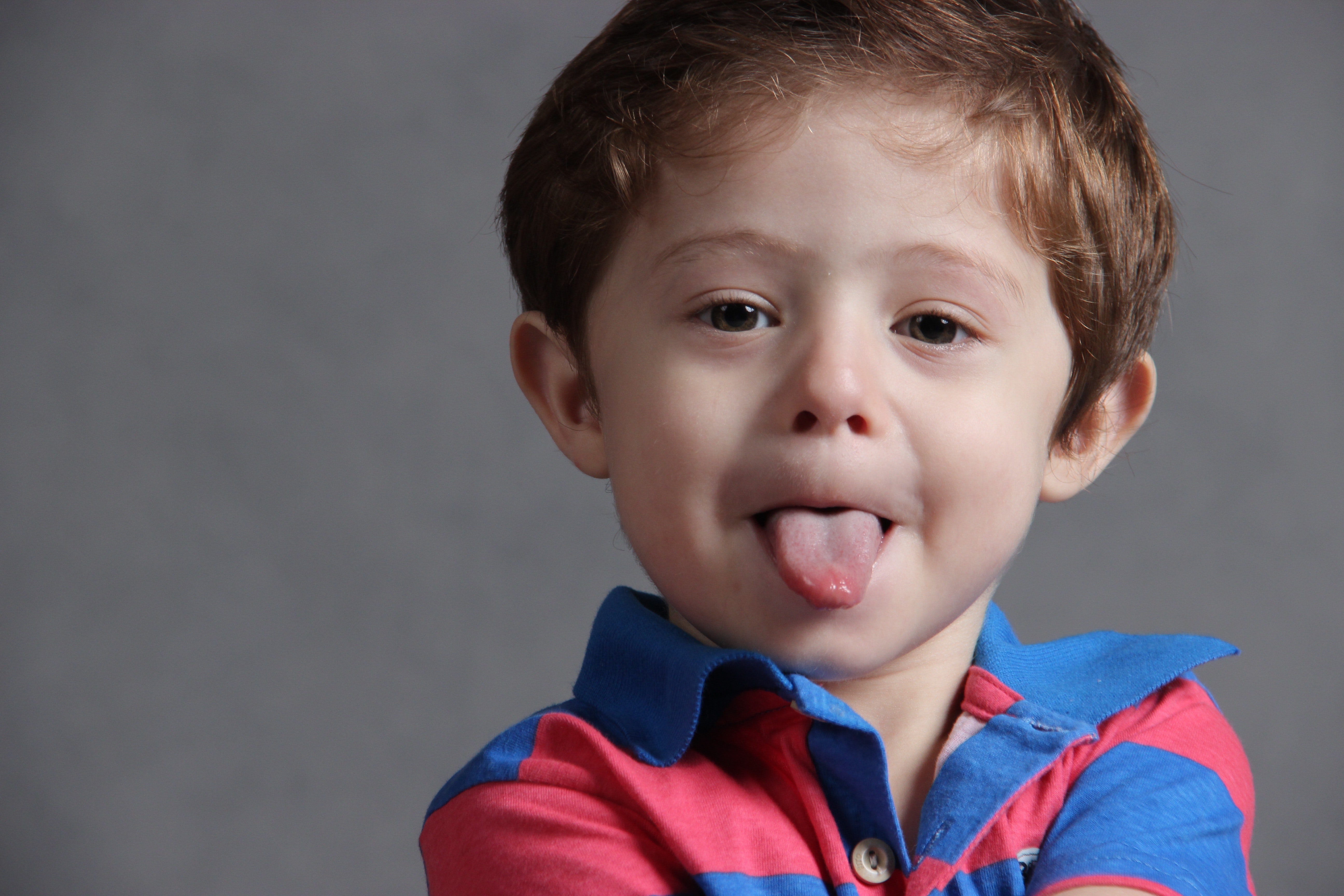 Child wearing blue and red stripes polo shirt sticking out tongue photo