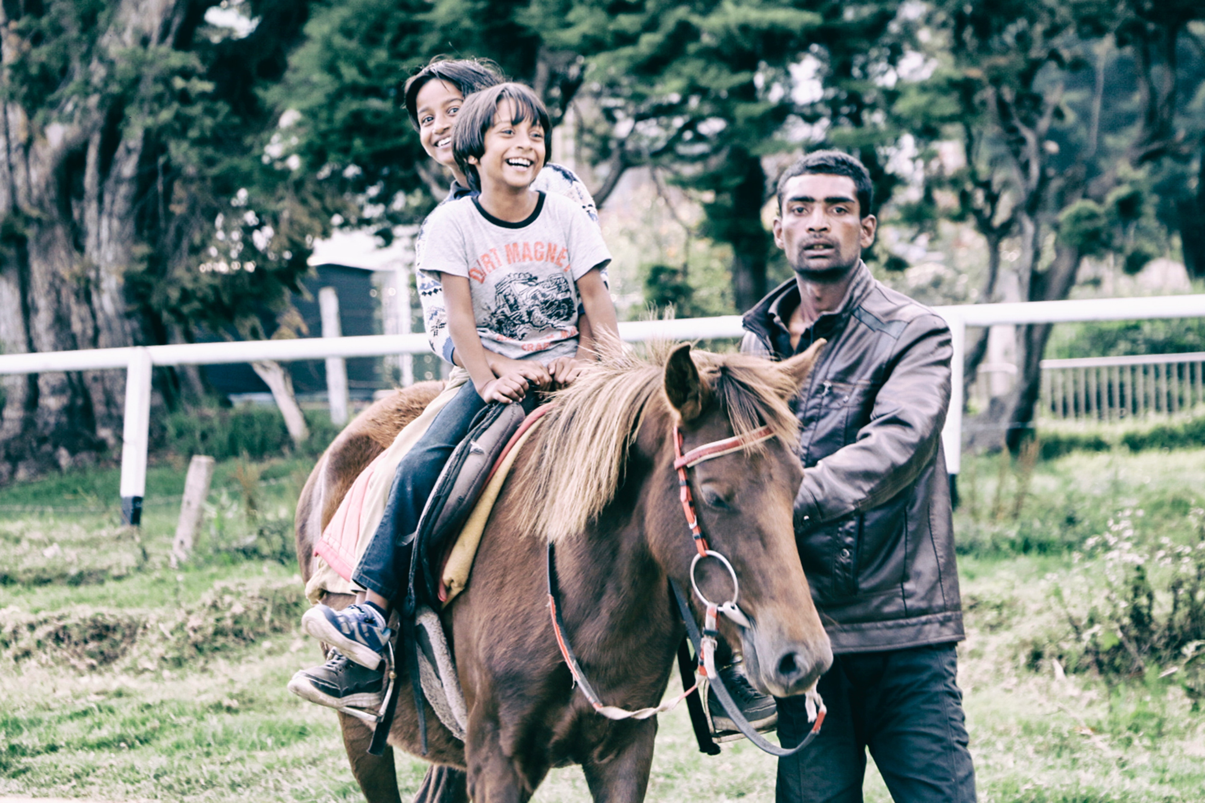 Children riding horse with adult guiding photo