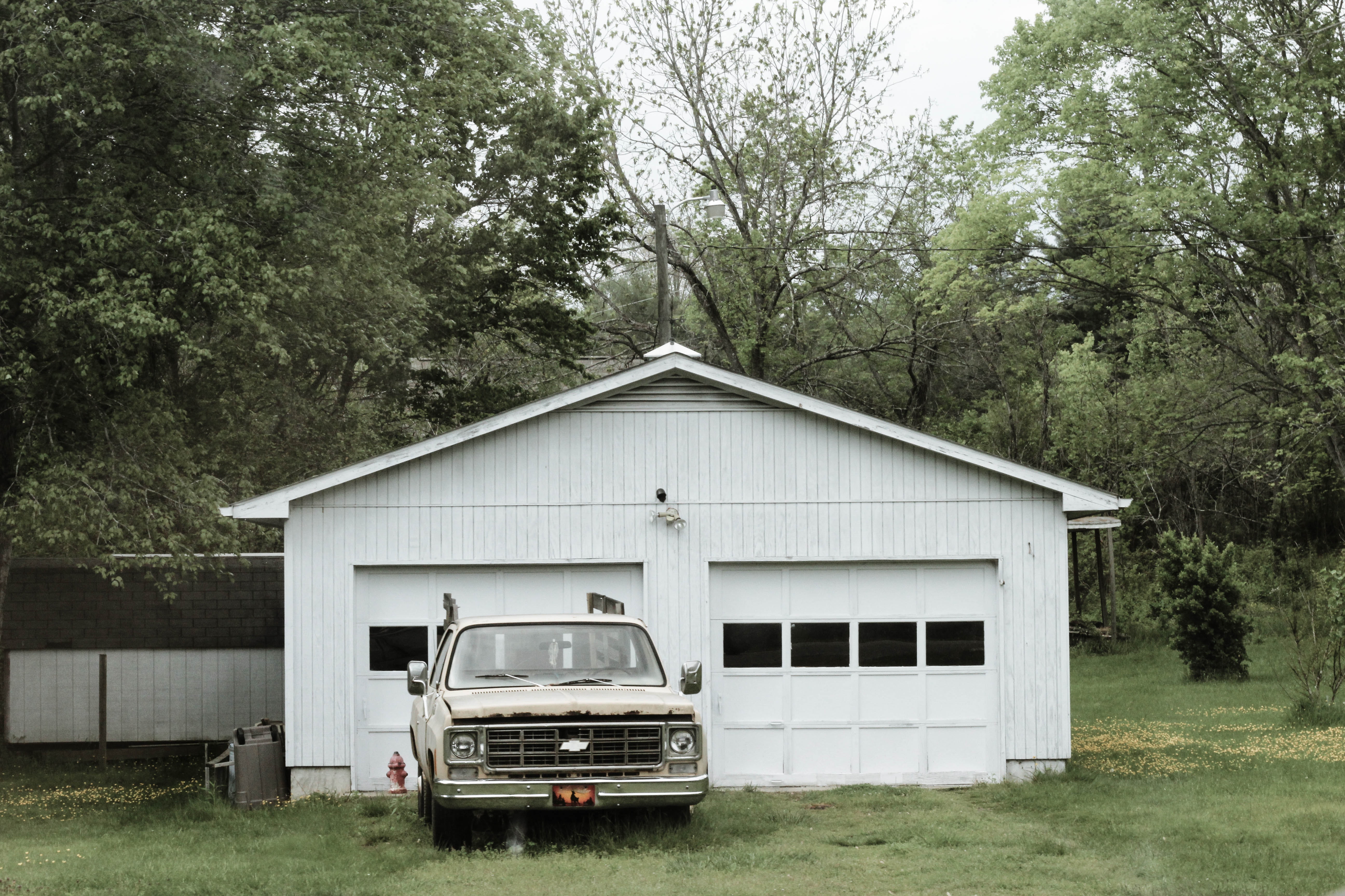 Classic white chevrolet pickup truck near white 2-door garage near trees photo
